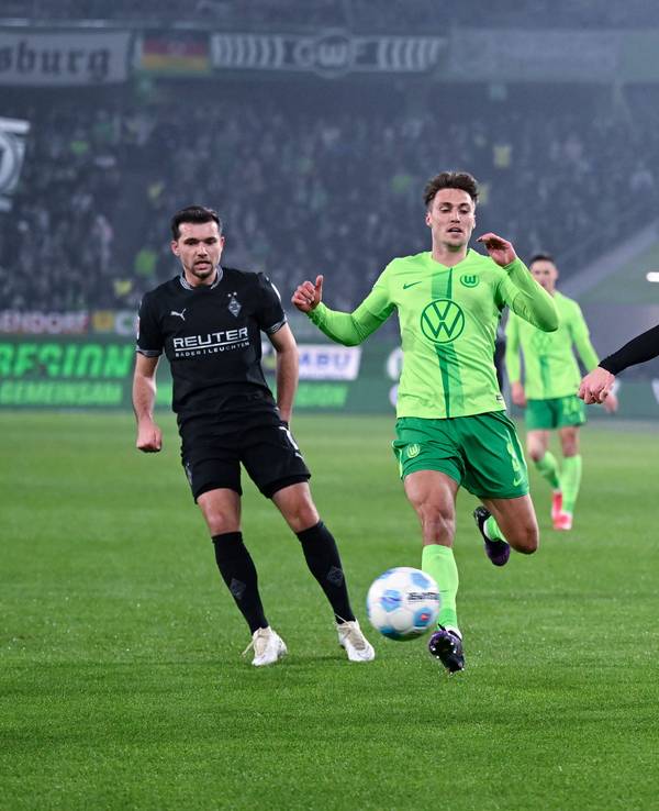 Borussia Mönchengladbachs Luca Netz schließt ab, Wolfsburgs Kilian Fischer kommt zu spät. Gladbachs Kevin Stöger beobachtet die Szene im Hintergrund.