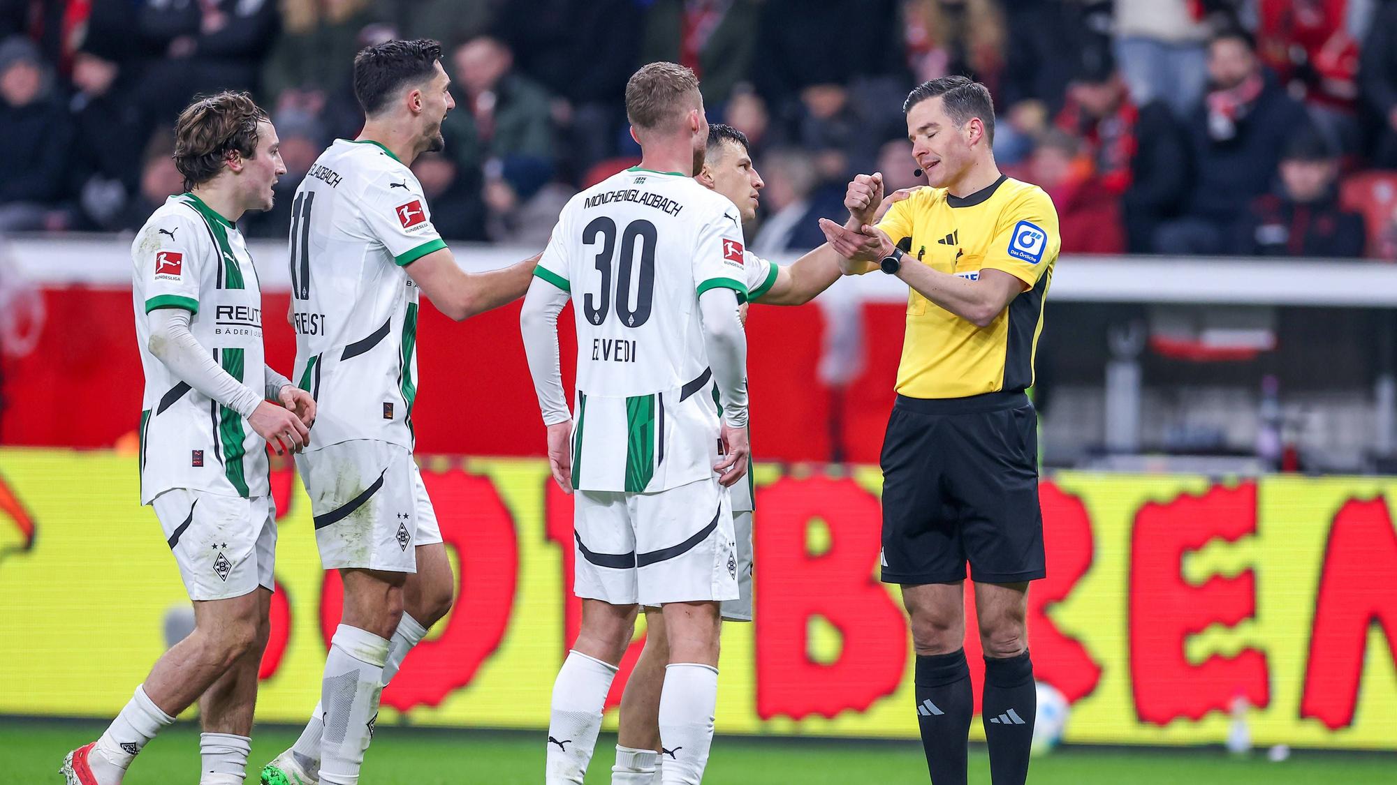 Spieler von Borussia Mönchengladbach beschweren sich beim Schiedsrichter.