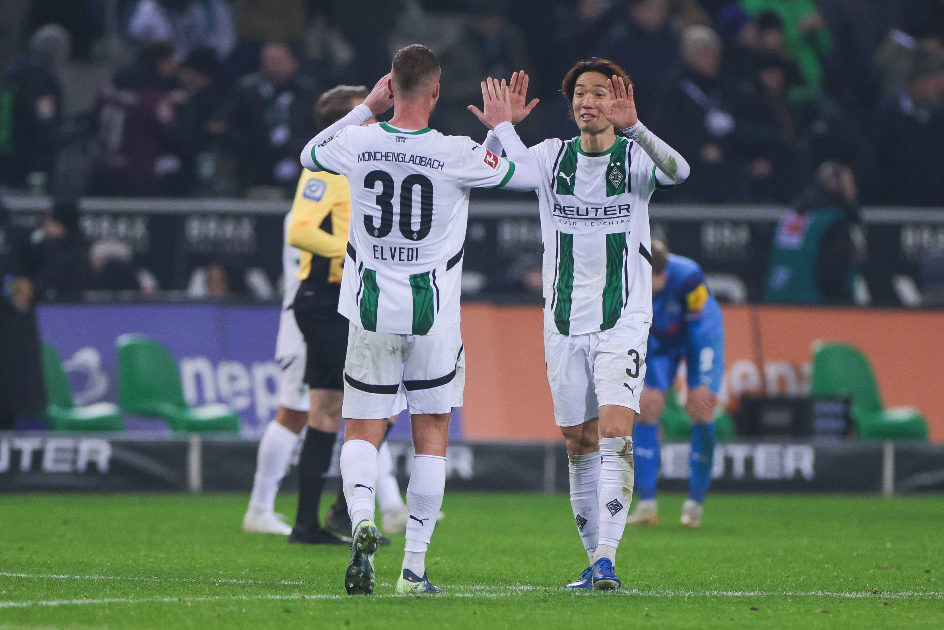 Die Borussia-Profis Ko Itakura und Nico Elvedi klatschen sich im Bundesliga-Spiel gegen Holstein Kiel ab.