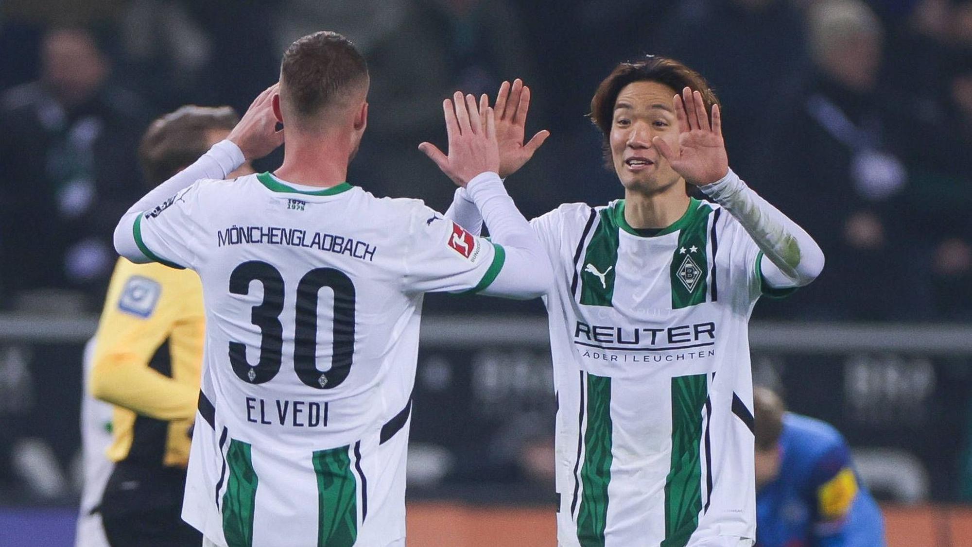 Die Borussia-Profis Ko Itakura und Nico Elvedi klatschen sich im Bundesliga-Spiel gegen Holstein Kiel ab.