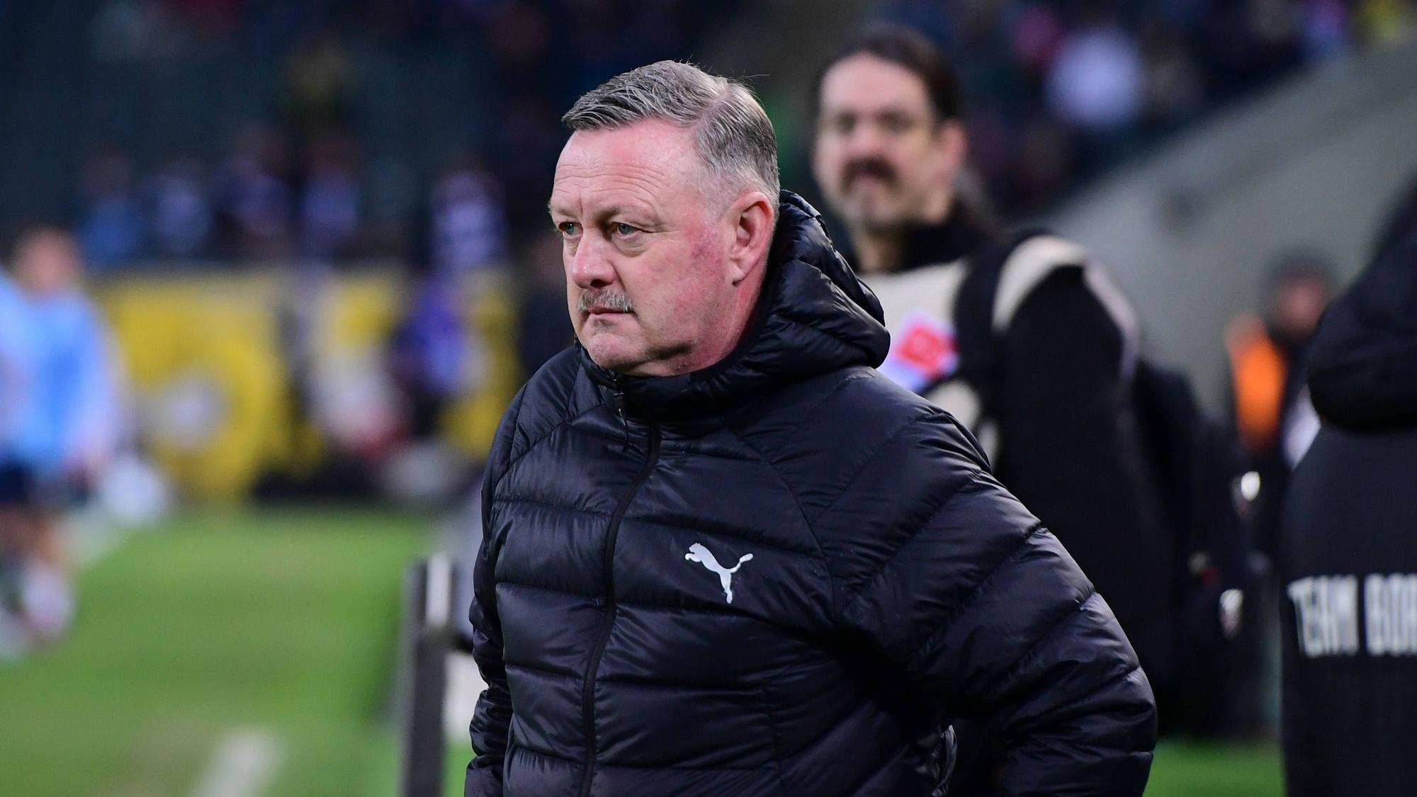 Roland Virkus überlegt am Spielfeldrand.
