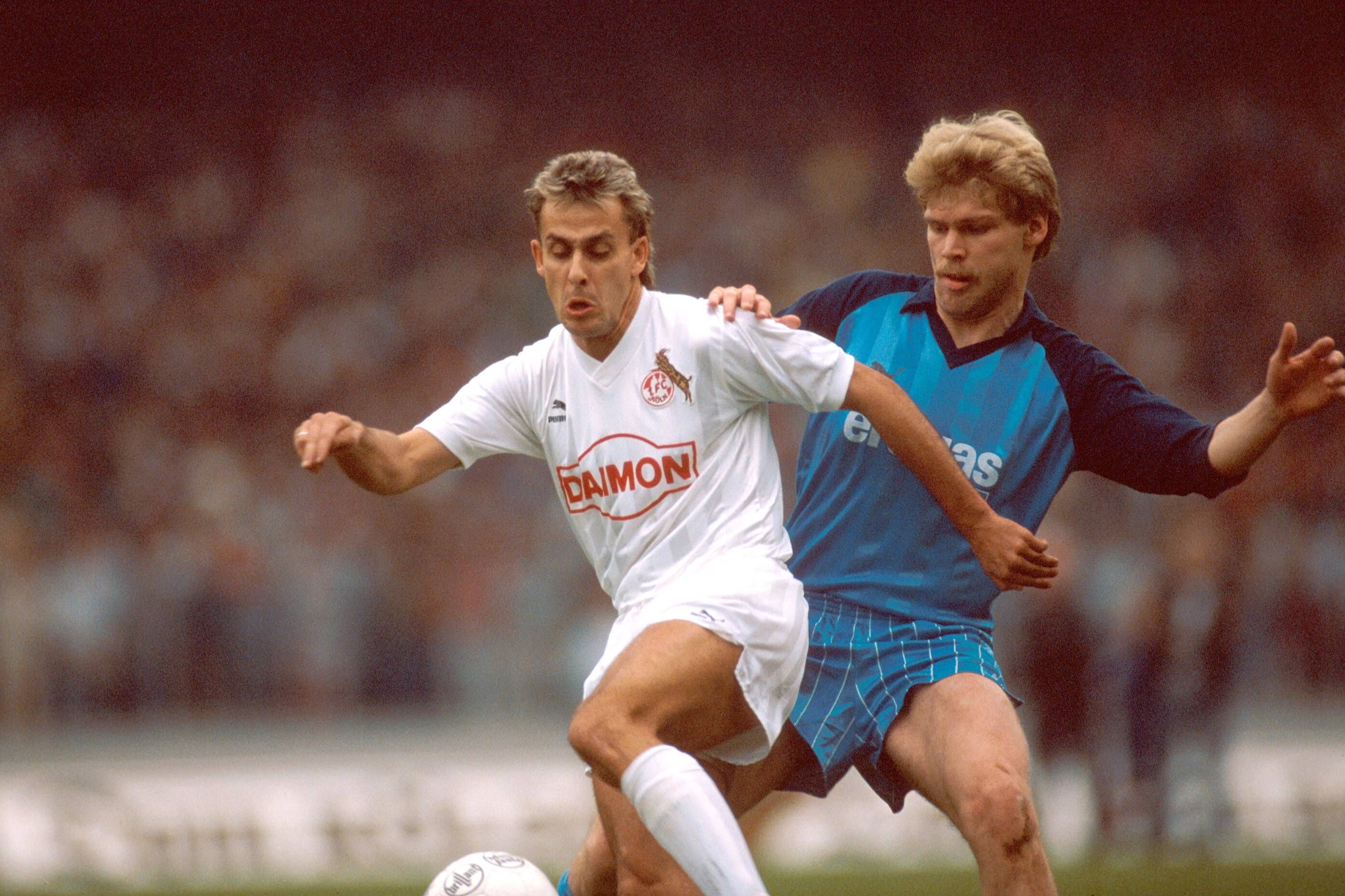 Ein Zweikampf im Derby, Dreßen trägt ein blaues Trikot, Littbarski in Weiß.