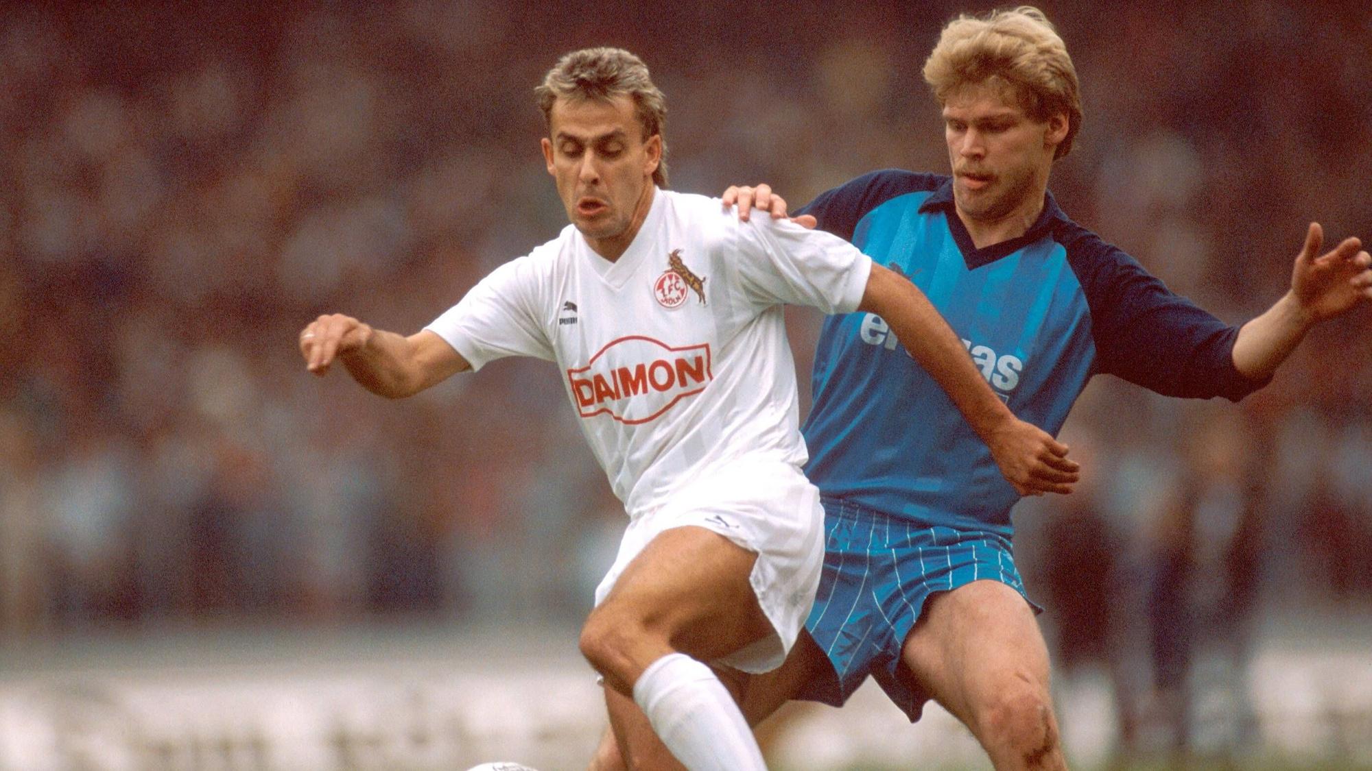 Ein Zweikampf im Derby, Dreßen trägt ein blaues Trikot, Littbarski in Weiß.