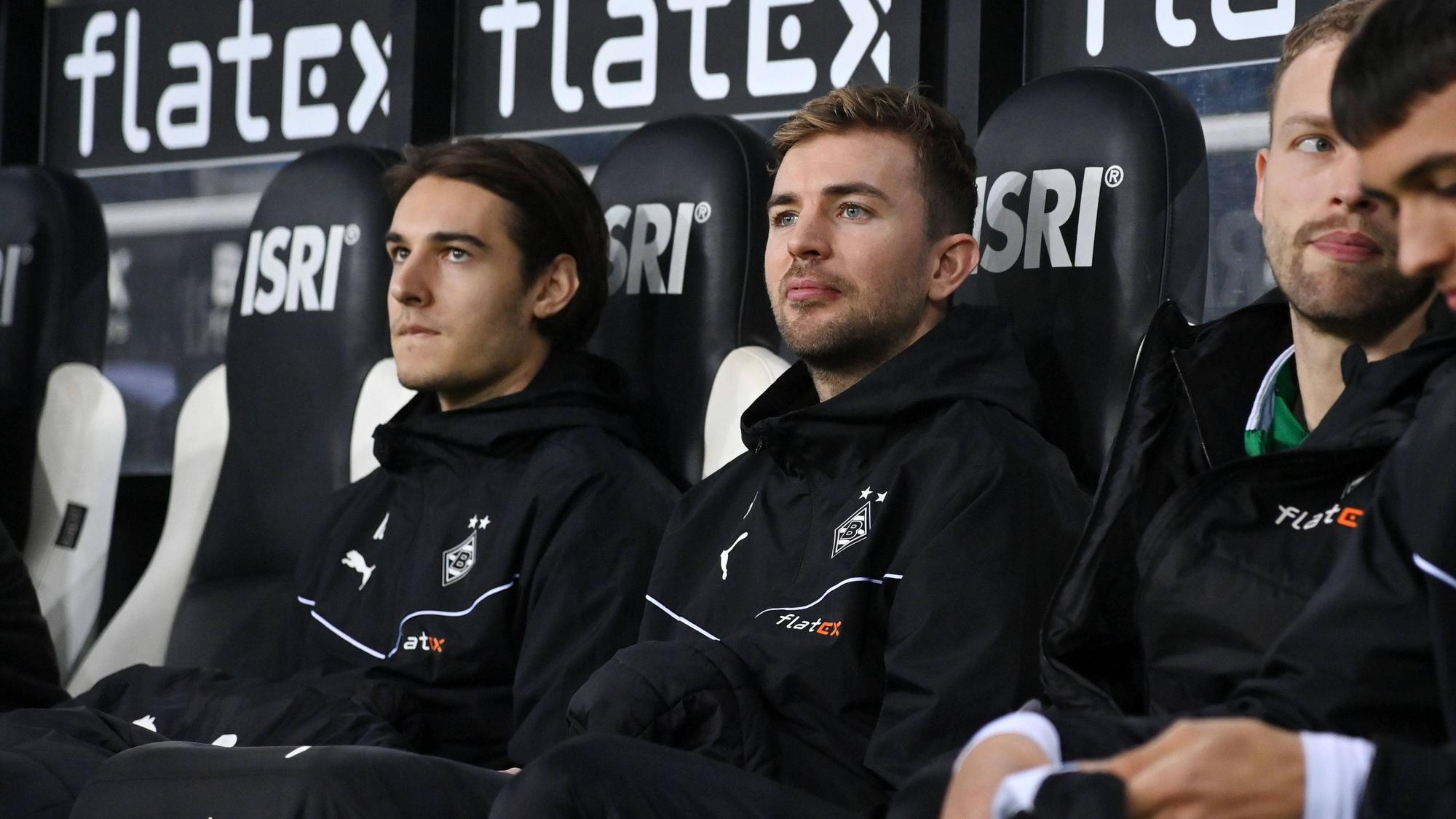 Christoph Kramer und Flo Neuhaus sitzen auf der Gladbach-Bank in Winterjacken und Decken.