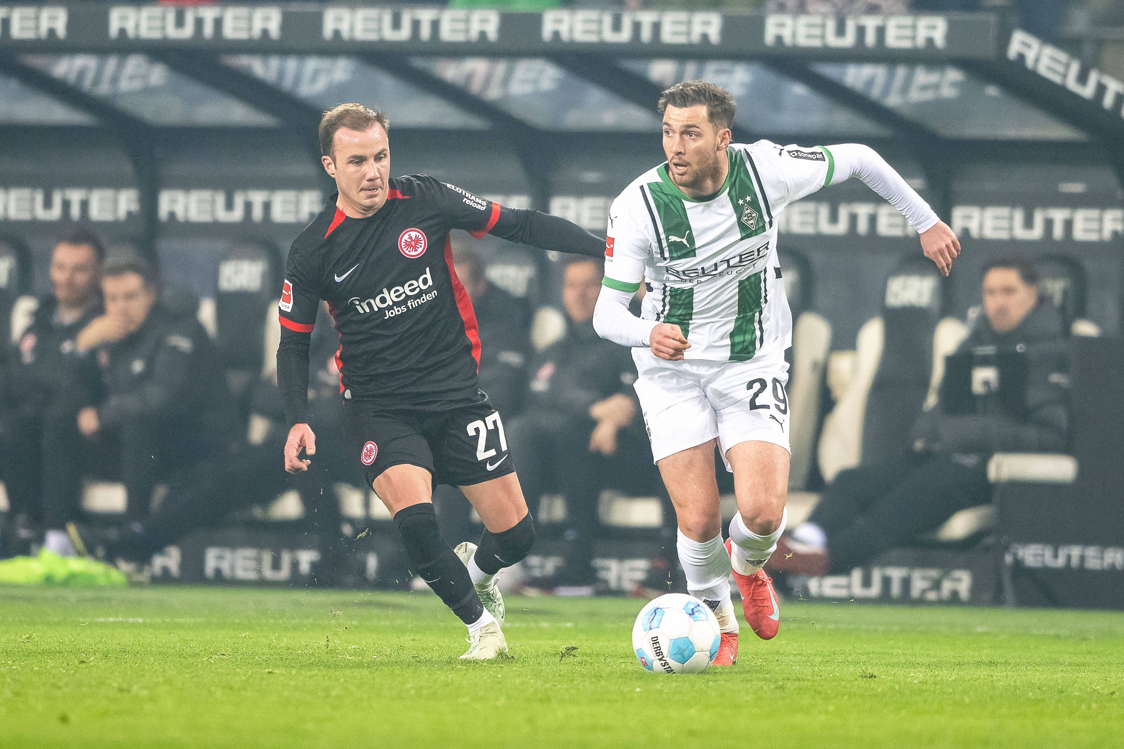 Borussia Mönchengladbachs Joe Scally führt den Ball, Eintracht Frankfurts Mario Götze verfolgt ihn.