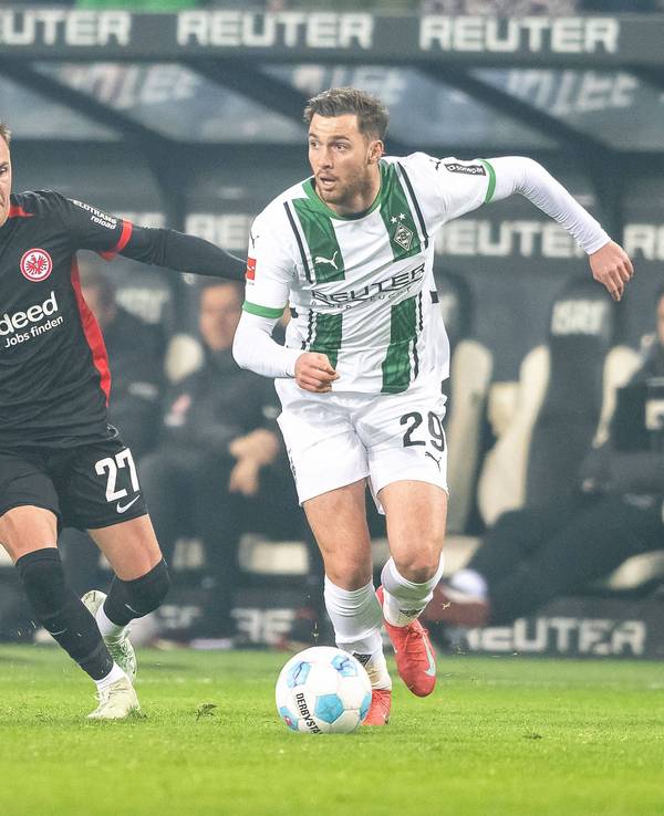 Borussia Mönchengladbachs Joe Scally führt den Ball, Eintracht Frankfurts Mario Götze verfolgt ihn.