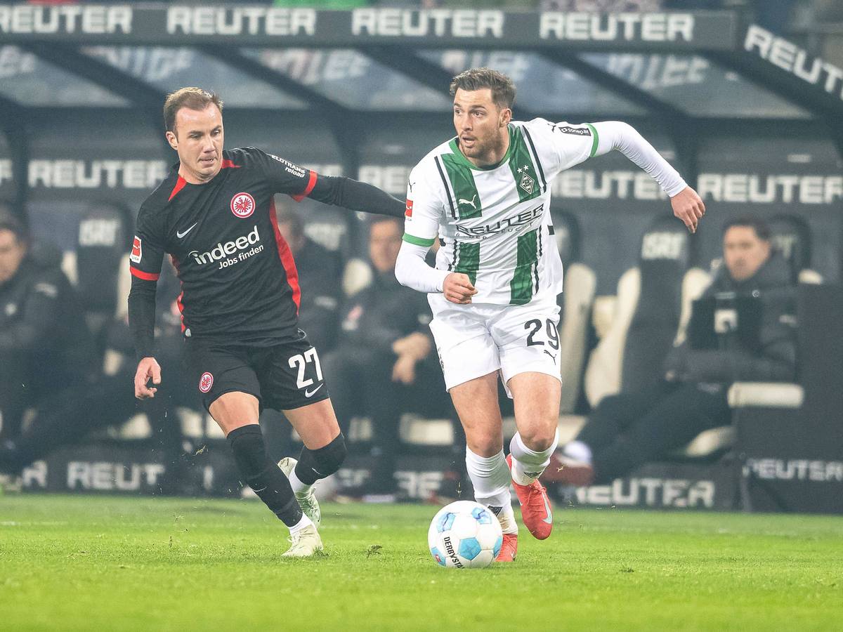 Borussia Mönchengladbachs Joe Scally führt den Ball, Eintracht Frankfurts Mario Götze verfolgt ihn.