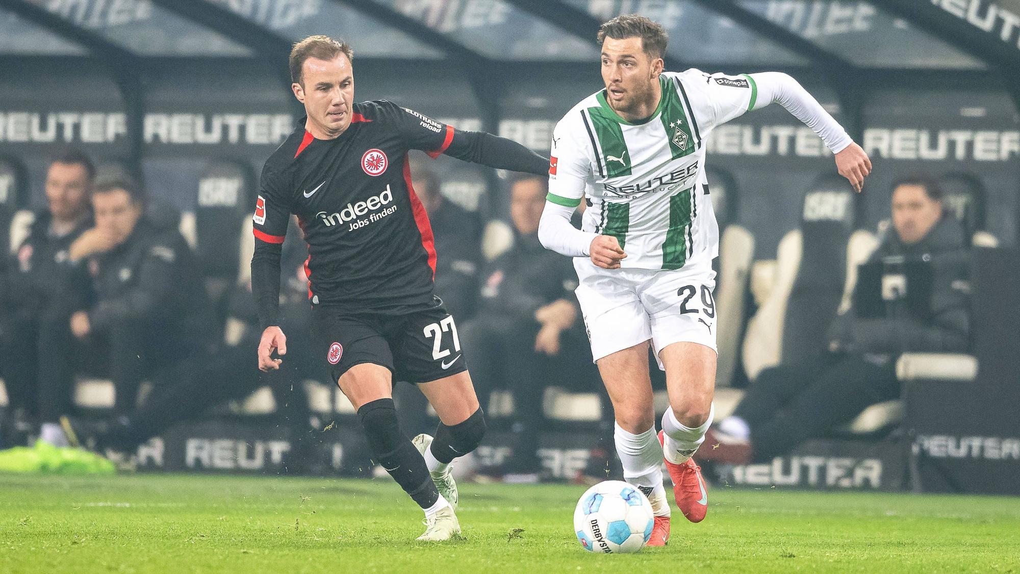 Borussia Mönchengladbachs Joe Scally führt den Ball, Eintracht Frankfurts Mario Götze verfolgt ihn.