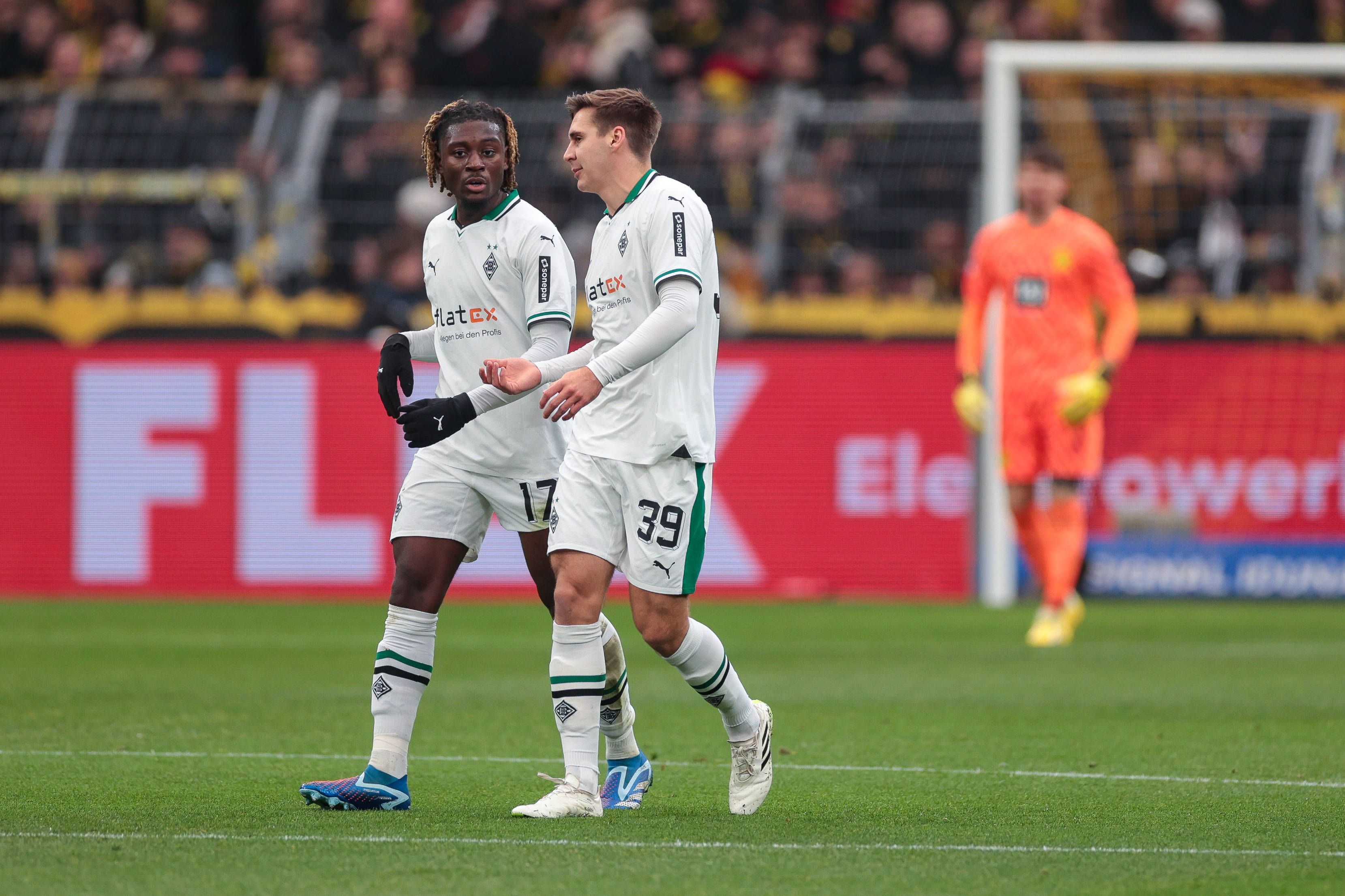 Die Gladbach-Profis Manu Koné und Maximilian Wöber laufen beim Spiel in Dortmund nebeneinander über den Rasen und unterhalten sich.