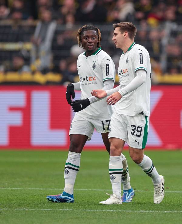 Die Gladbach-Profis Manu Koné und Maximilian Wöber laufen beim Spiel in Dortmund nebeneinander über den Rasen und unterhalten sich.