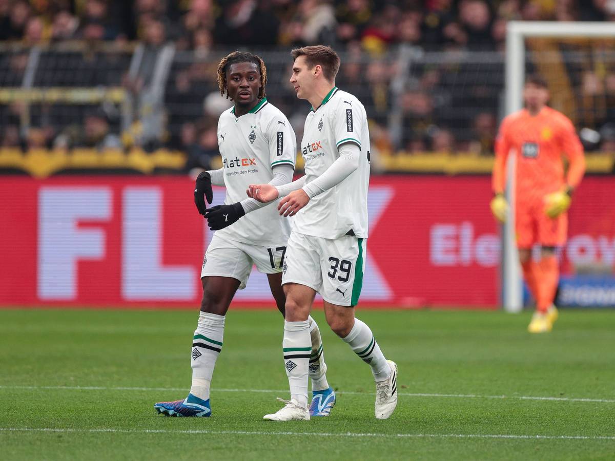 Die Gladbach-Profis Manu Koné und Maximilian Wöber laufen beim Spiel in Dortmund nebeneinander über den Rasen und unterhalten sich.