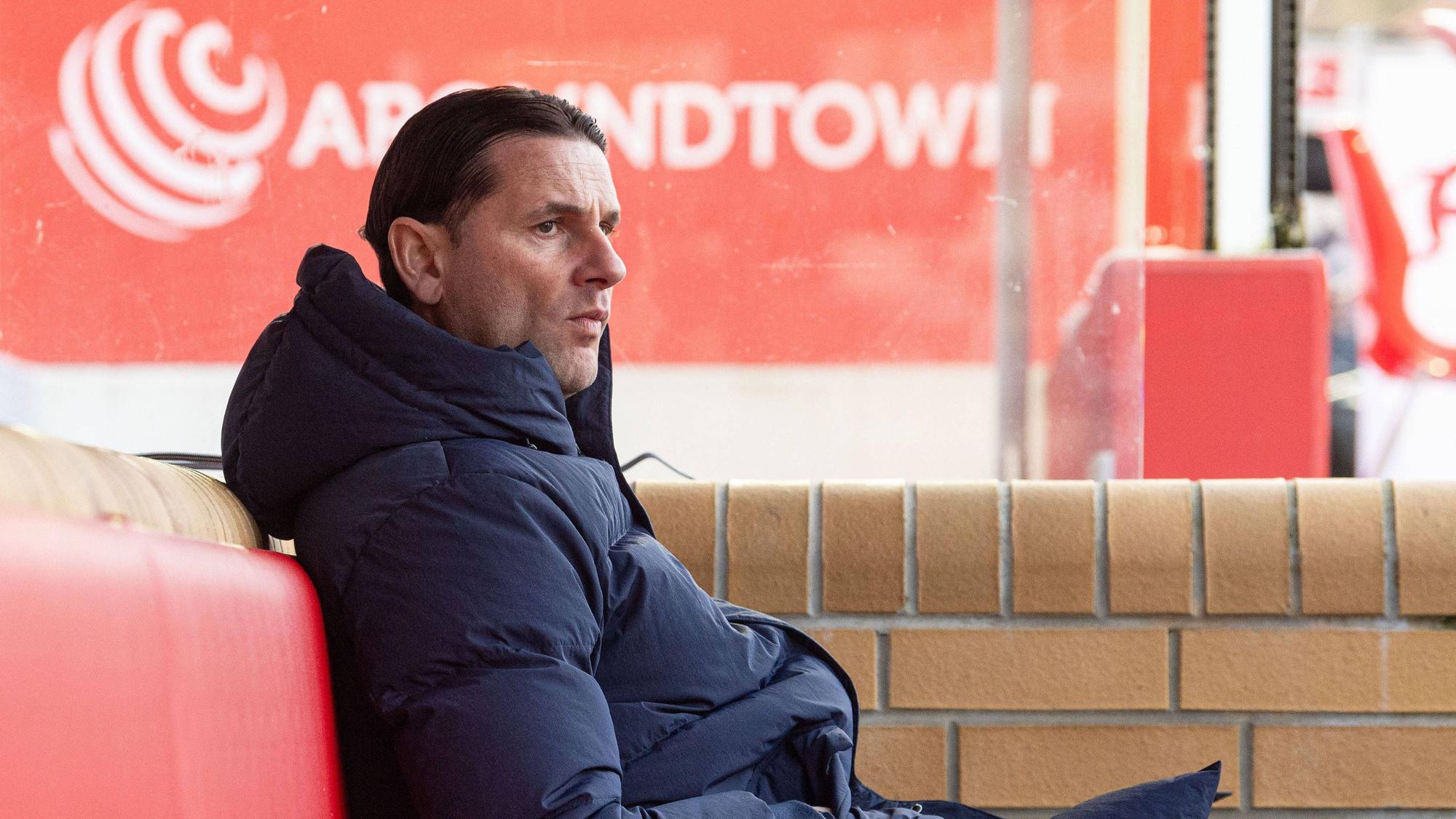 Borussia Mönchengladbachs Trainer Gerardo Seoane sitzt während des Bundesliga-Auswärtsspiels bei Union Berlin auf der Bank, hat die Hände in den Taschen vergraben und blickt skeptisch aufs Spielfeld.