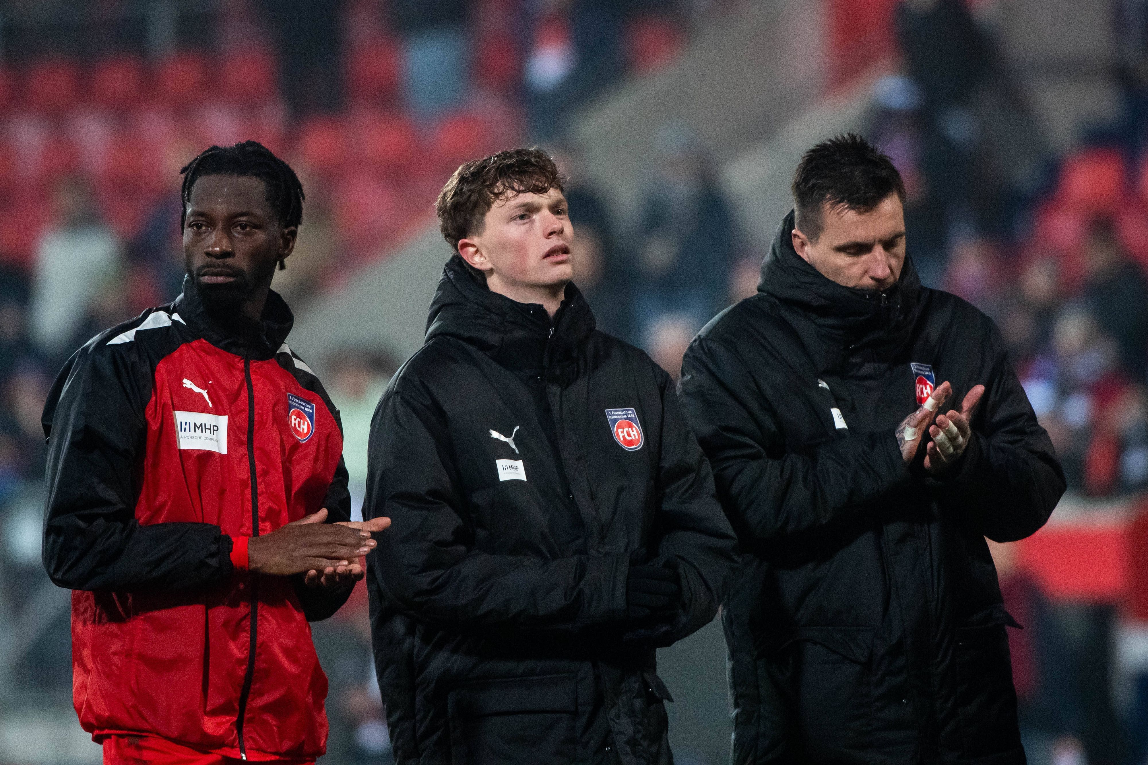 Die Heidenheim-Profis Omar Traoré, Paul Wanner und Kevin Müller stehen nach dem Playoff-Rückspiel in der Conference League gegen den FC Kopenhagen enttäuscht vor der Kurve und applaudieren den Fans.