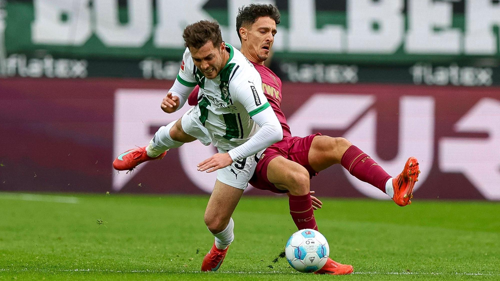Borussia Mönchengladbachs Joe Scally und Augsburgs Dimitrios Giannoulis kämpfen um den Ball.