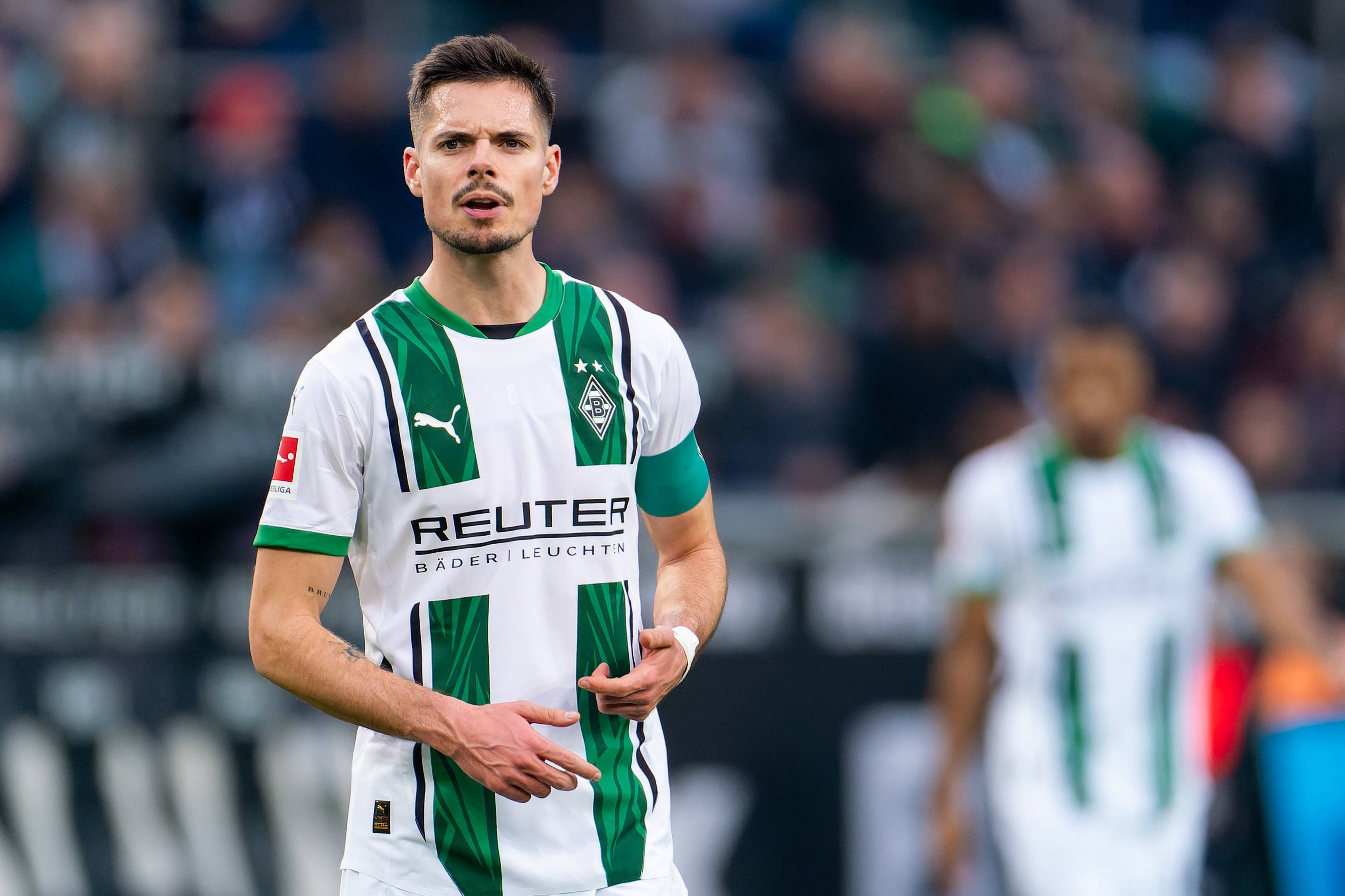 Borussia Mönchengladbachs Julian Weigl steht im Bundesliga-Spiel gegen den FC Augsburg auf dem Platz und verzieht das Gesicht.
