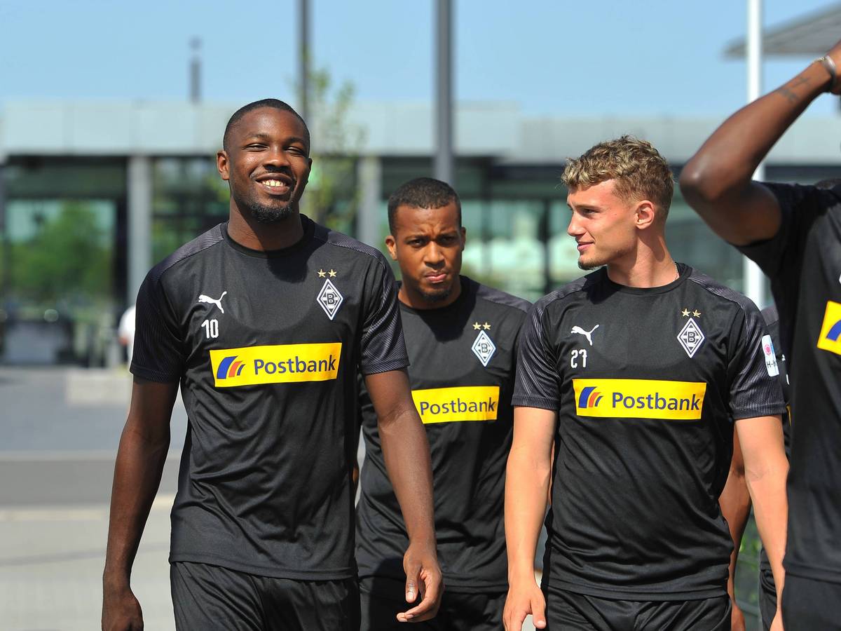 Die Gladbacher gehen am Borussia-Park in der Sonne zum Trainingsplatz.