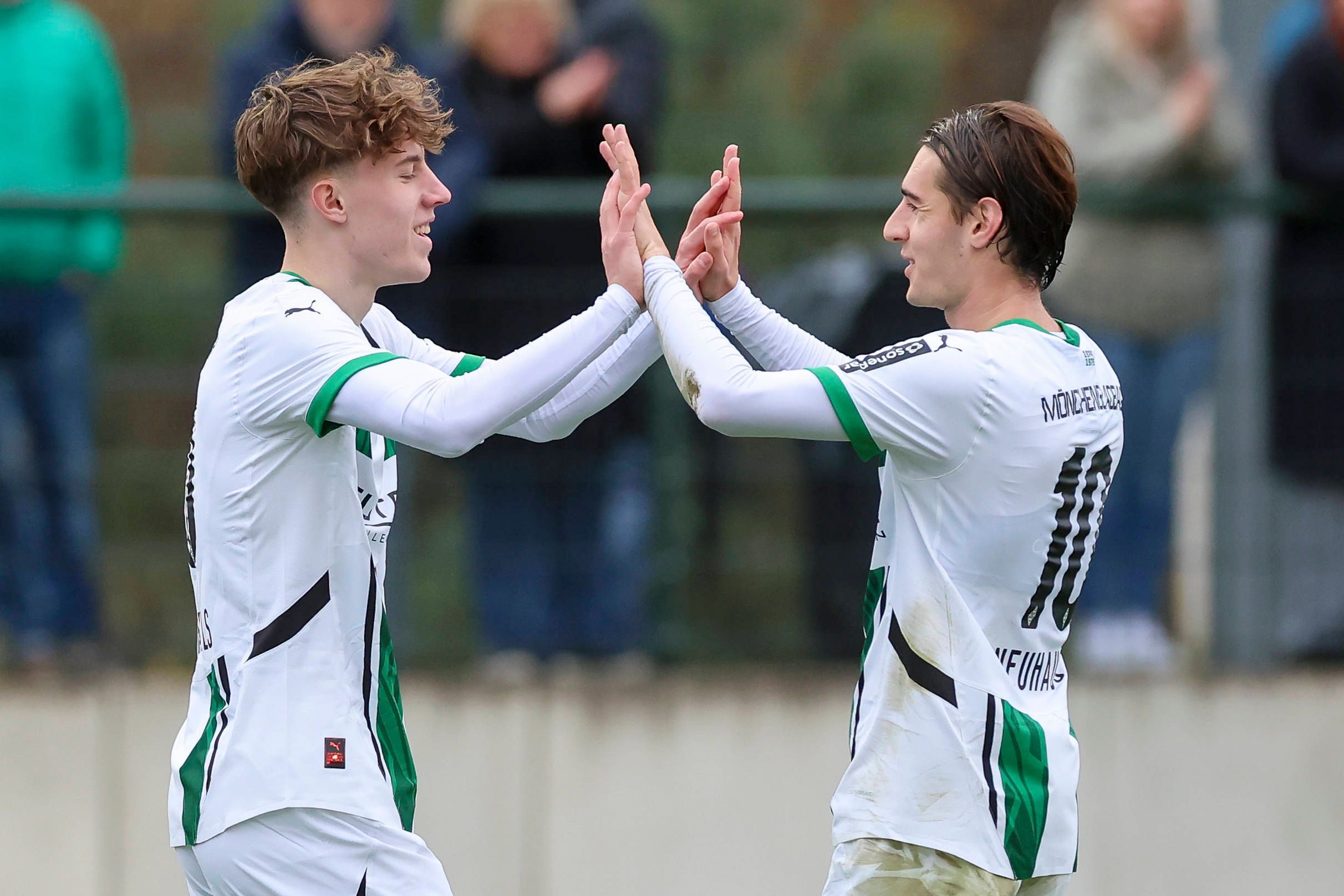 Angreifer Yannick Michaelis und Mittelfeldspieler Florian Neuhaus klatschen sich im Spiel ihres Klubs Borussia Mönchengladbach gegen Preußen Münster ab.