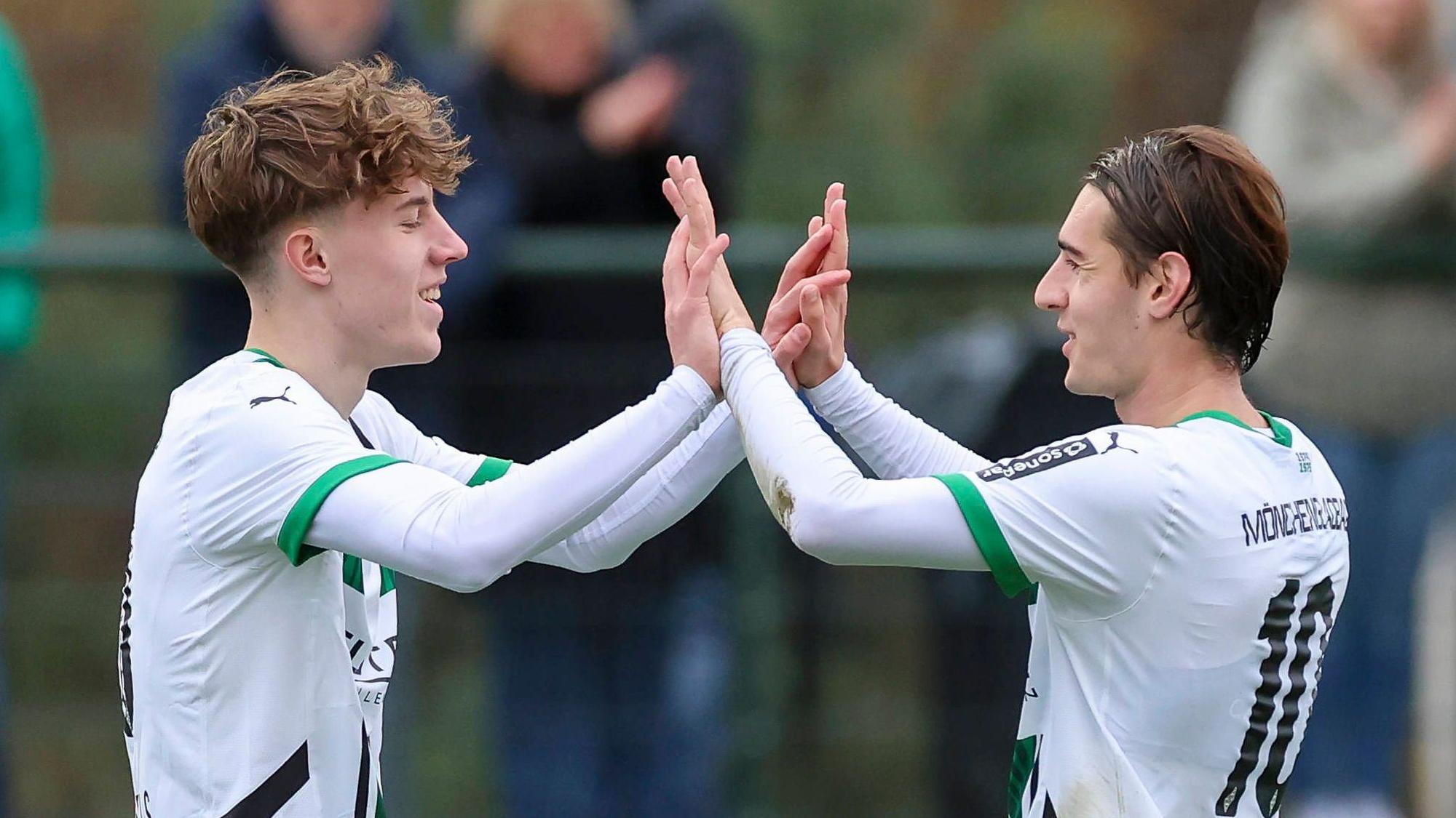 Angreifer Yannick Michaelis und Mittelfeldspieler Florian Neuhaus klatschen sich im Spiel ihres Klubs Borussia Mönchengladbach gegen Preußen Münster ab.