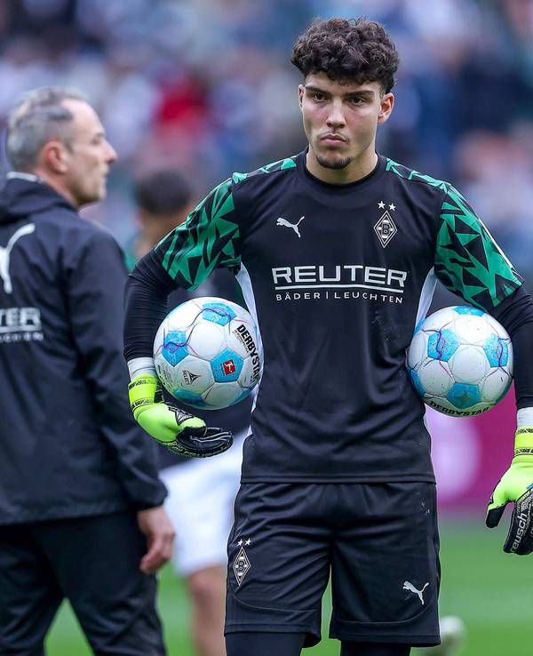 Borussia Mönchengladbachs Torwart Tiago Pereira Cardoso steht vor dem Bundesliga-Spiel gegen den FC Augsburg auf dem Platz und hält links und rechts zwei Bälle unter dem Arm.