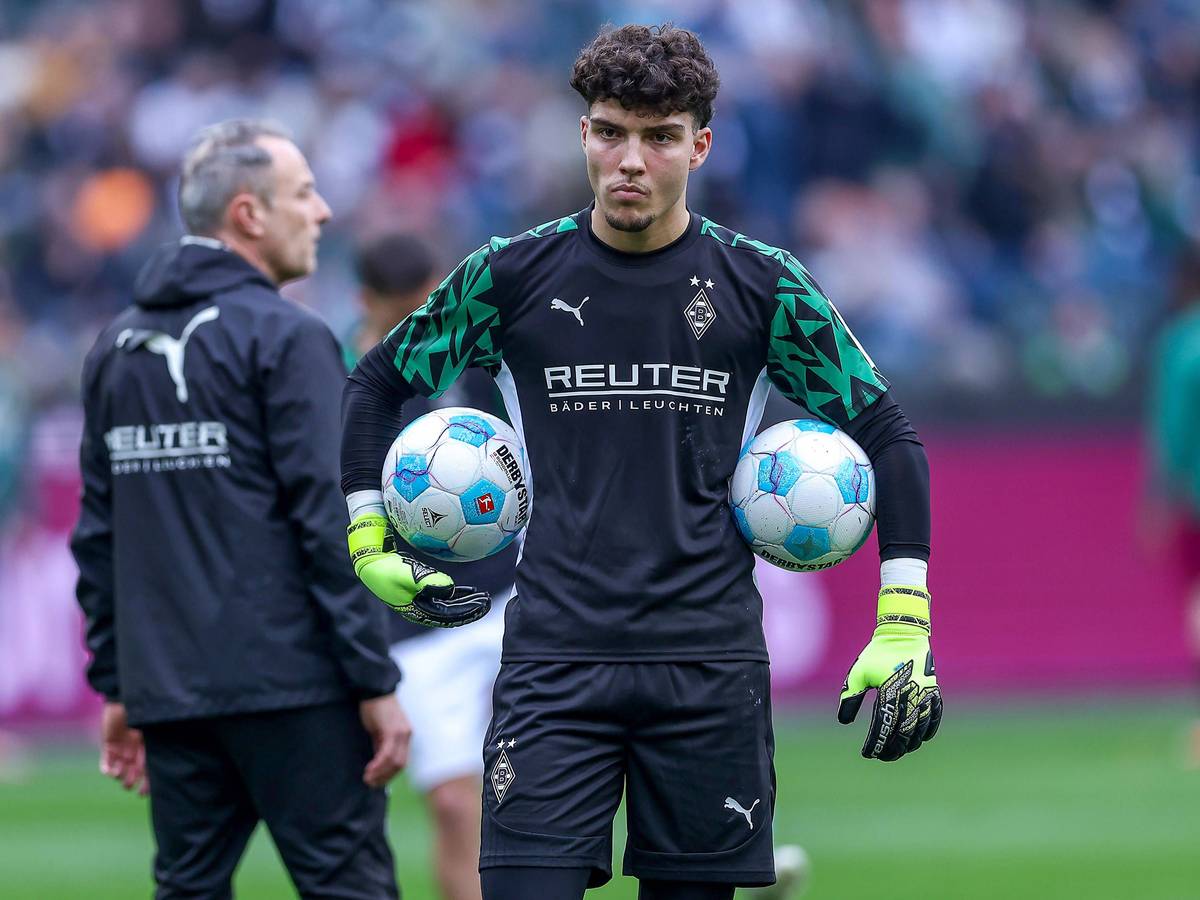 Borussia Mönchengladbachs Torwart Tiago Pereira Cardoso steht vor dem Bundesliga-Spiel gegen den FC Augsburg auf dem Platz und hält links und rechts zwei Bälle unter dem Arm.