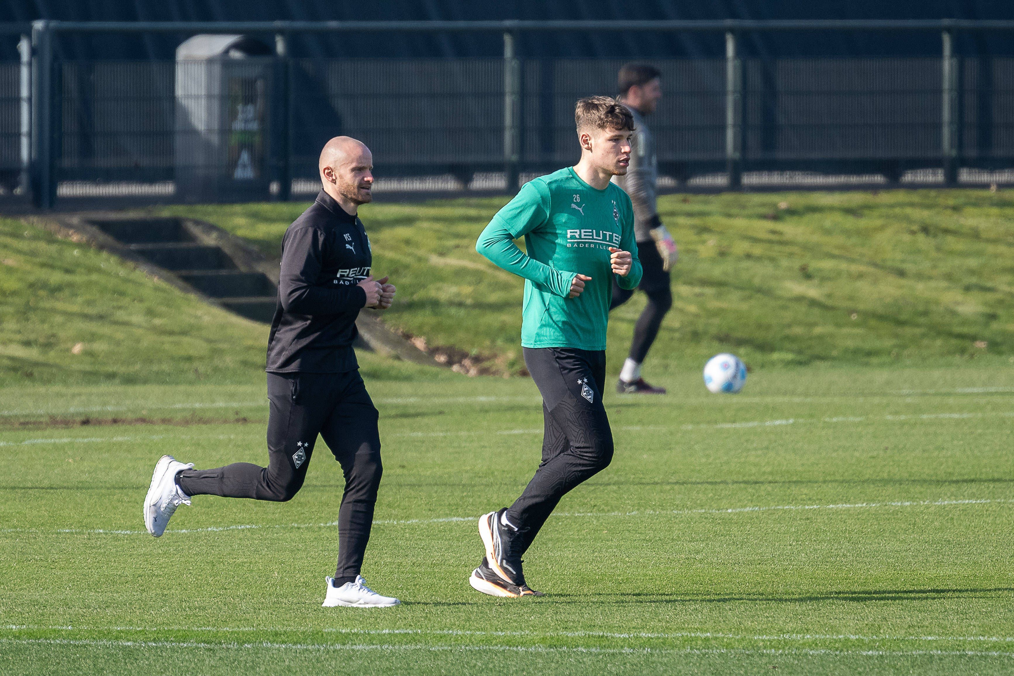 Borussia Mönchengladbachs Lukas Ullrich läuft, begleitet von Athletik-Trainer Philipp Schmidt, über den Trainingsplatz.