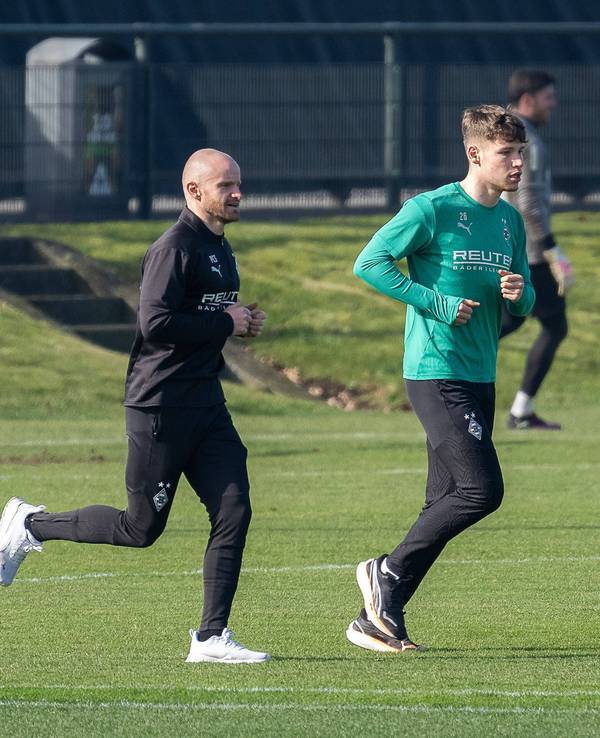Borussia Mönchengladbachs Lukas Ullrich läuft, begleitet von Athletik-Trainer Philipp Schmidt, über den Trainingsplatz.
