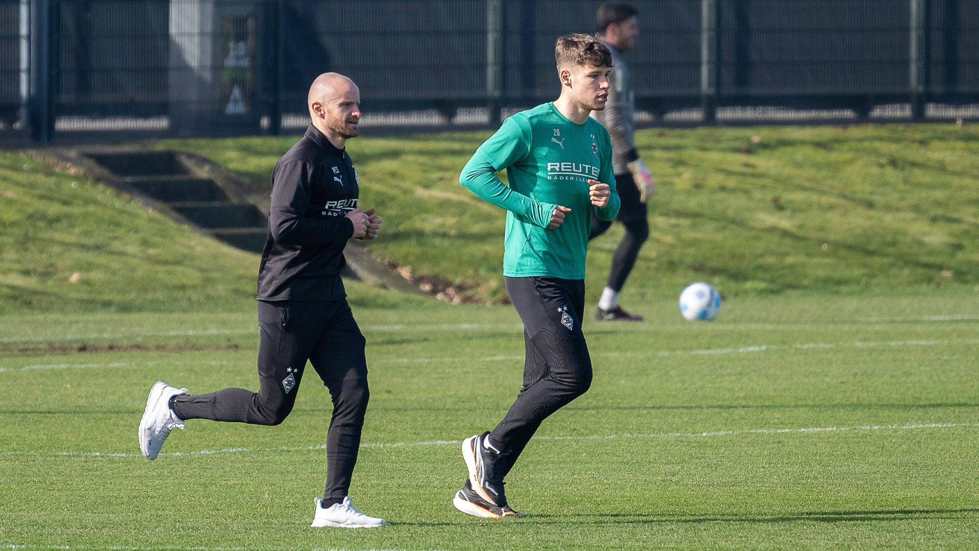 Borussia Mönchengladbachs Lukas Ullrich läuft, begleitet von Athletik-Trainer Philipp Schmidt, über den Trainingsplatz.
