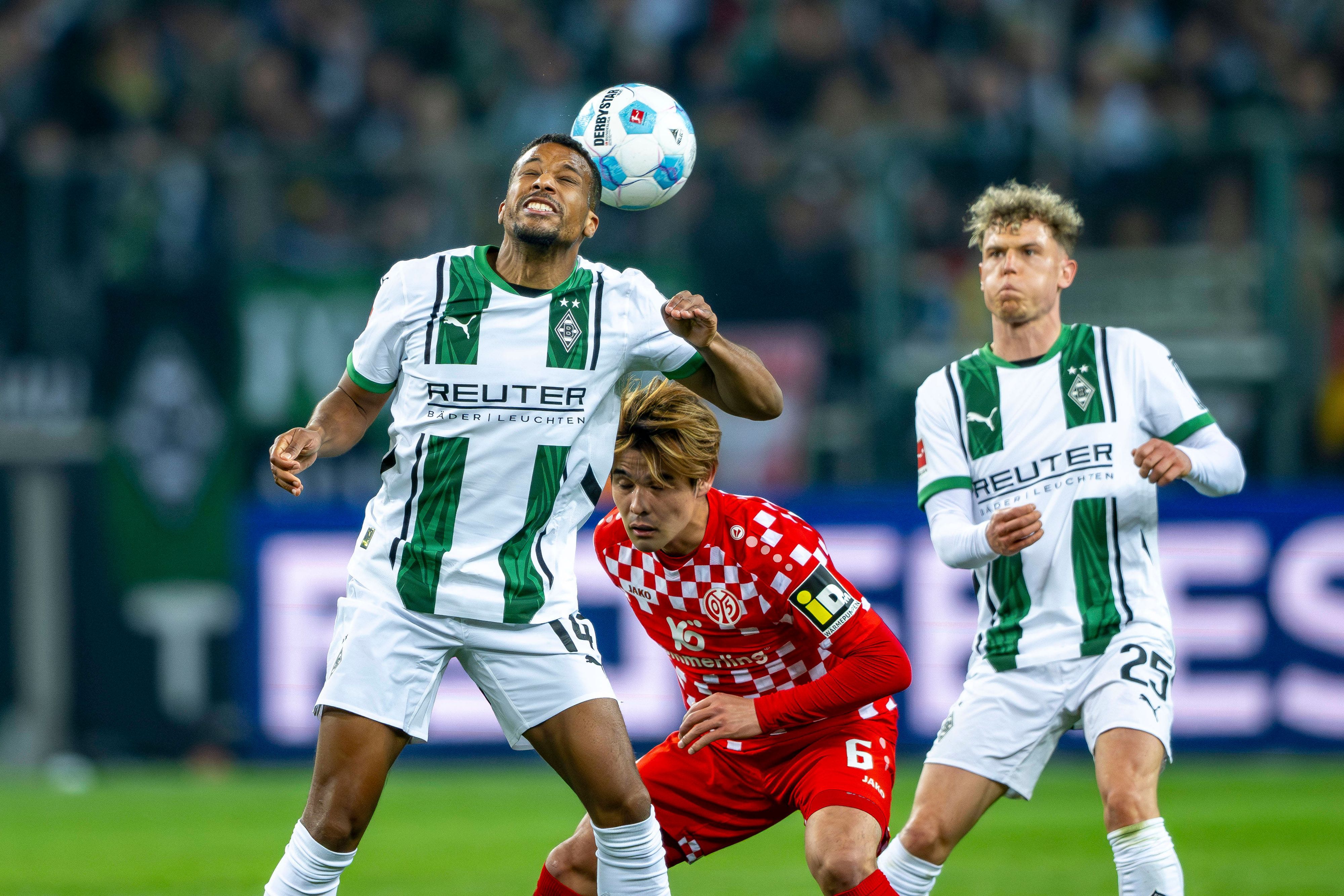 Borussia Mönchengladbachs Alassane Plea köpft den Ball, Mainz-Profi Kaishu Sano steht dahinter, Gladbachs Robin Hack beobachtet die Szene.