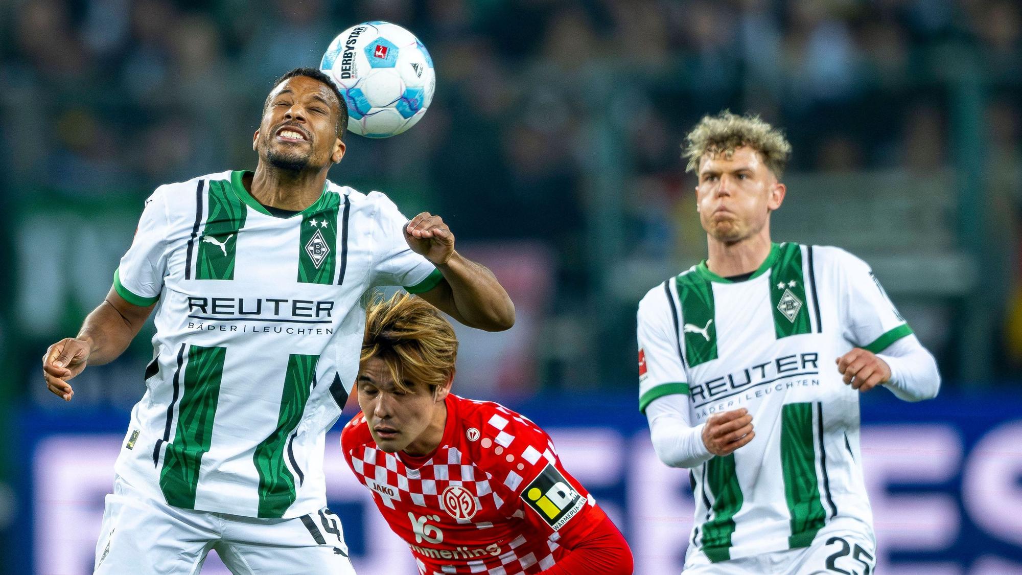 Borussia Mönchengladbachs Alassane Plea köpft den Ball, Mainz-Profi Kaishu Sano steht dahinter, Gladbachs Robin Hack beobachtet die Szene.