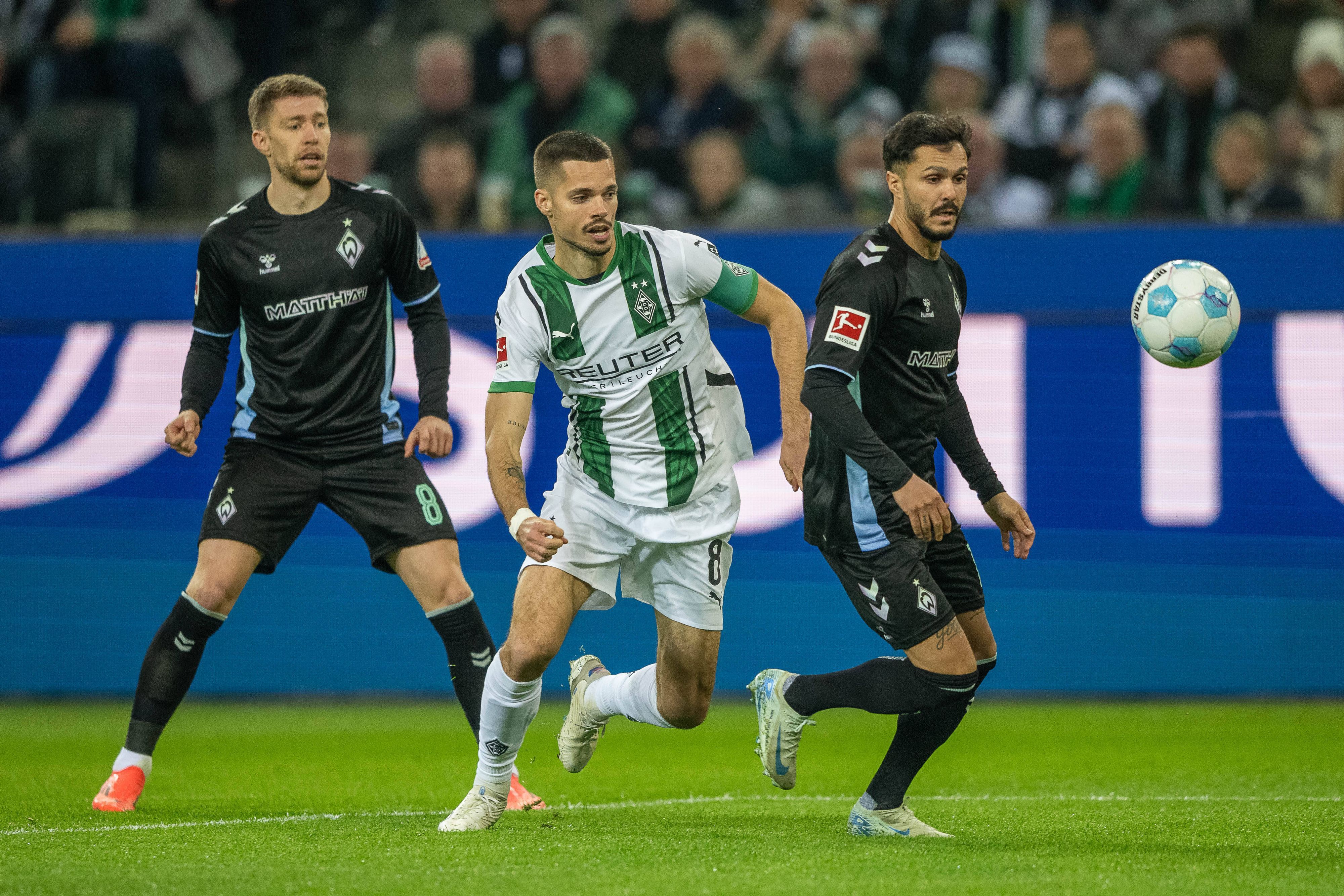 Borussia Mönchengladbachs Julian Weigl steht hinter Bremens Leonardo Bittencourt und hat den Ball im Blick, im Hintergrund beobachtet Werders Mitchell Weiser die Szene.