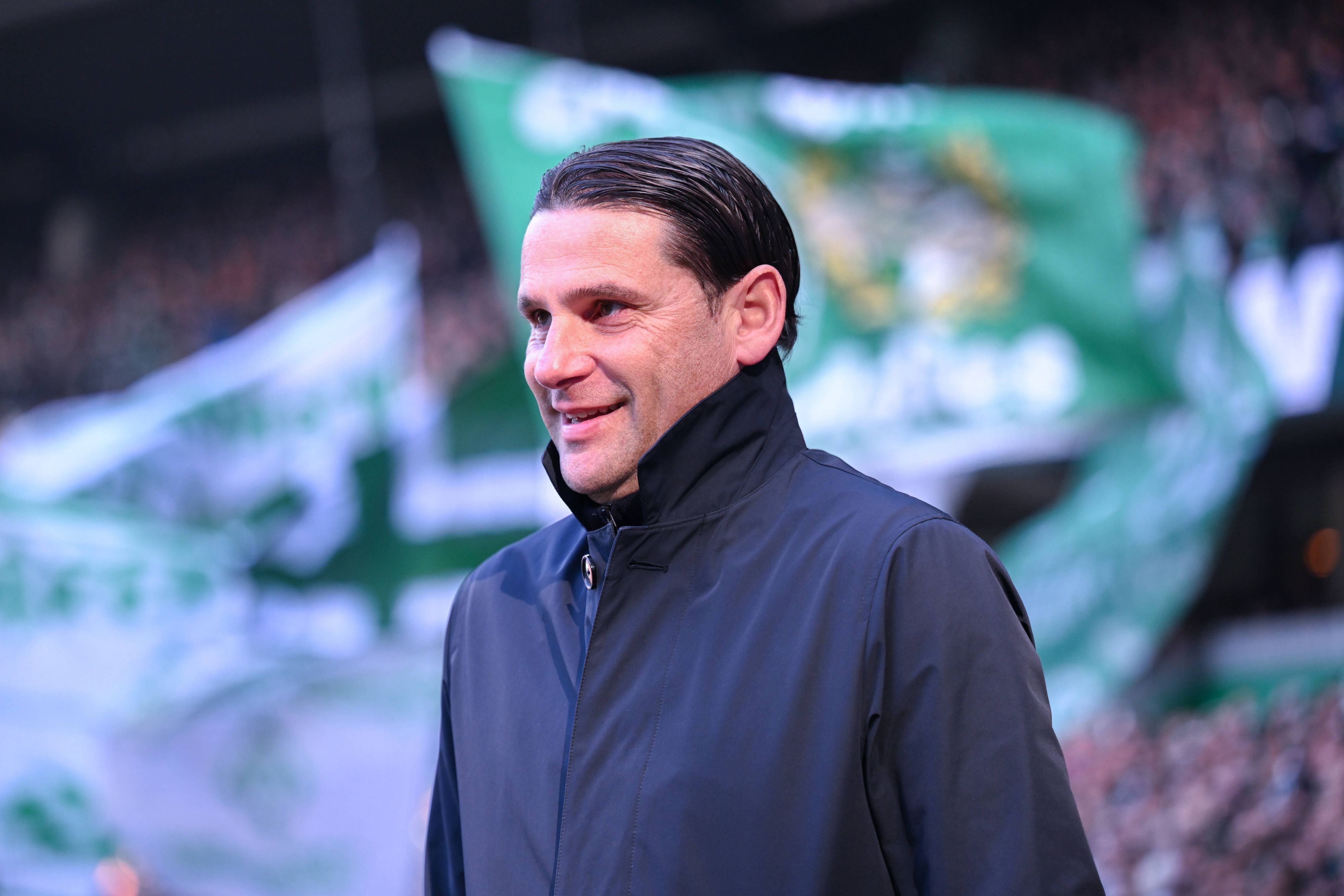 Gerardo Seoane lächelt vor der Kurve der Bremen-Fans.