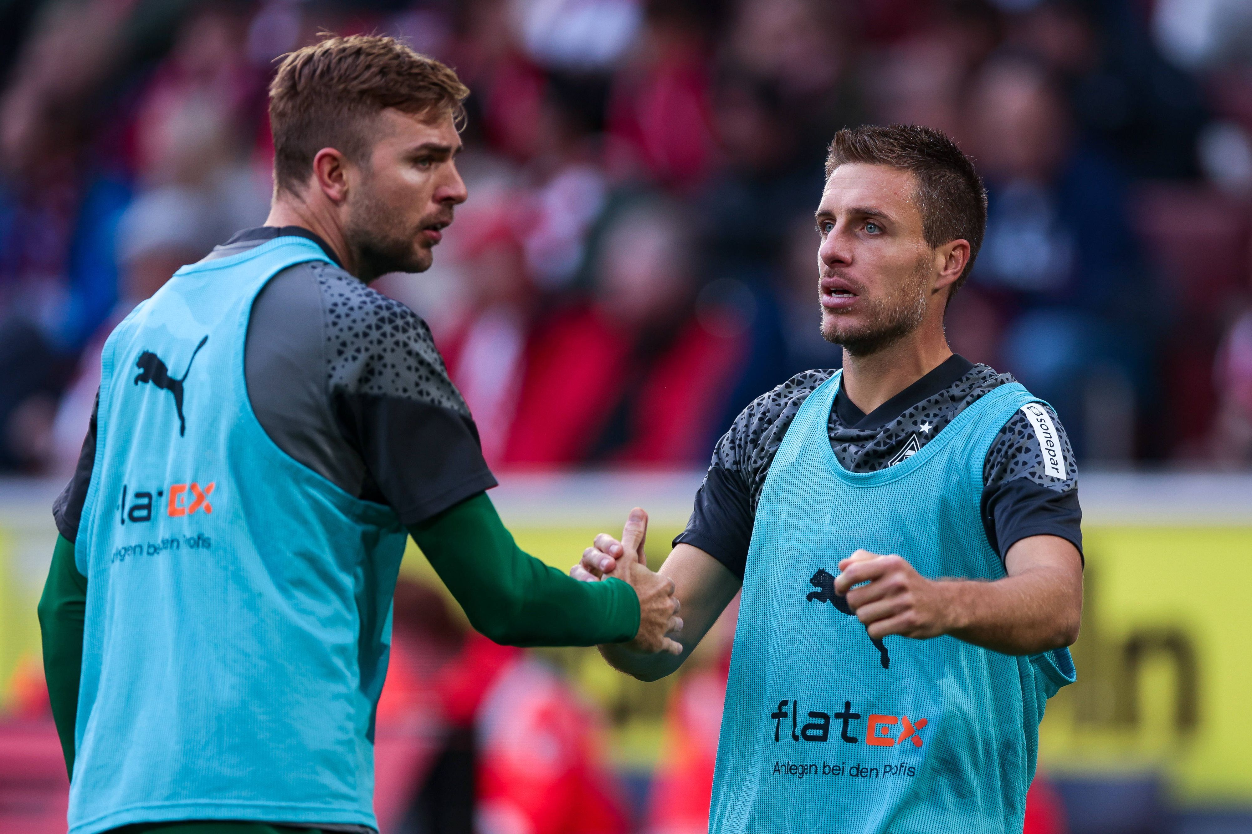 Die Gladbach-Reservisten Christoph Kramer und Patrick Herrmann klatschen sich während des Spiels beim 1. FC Köln auf dem Platz ab.