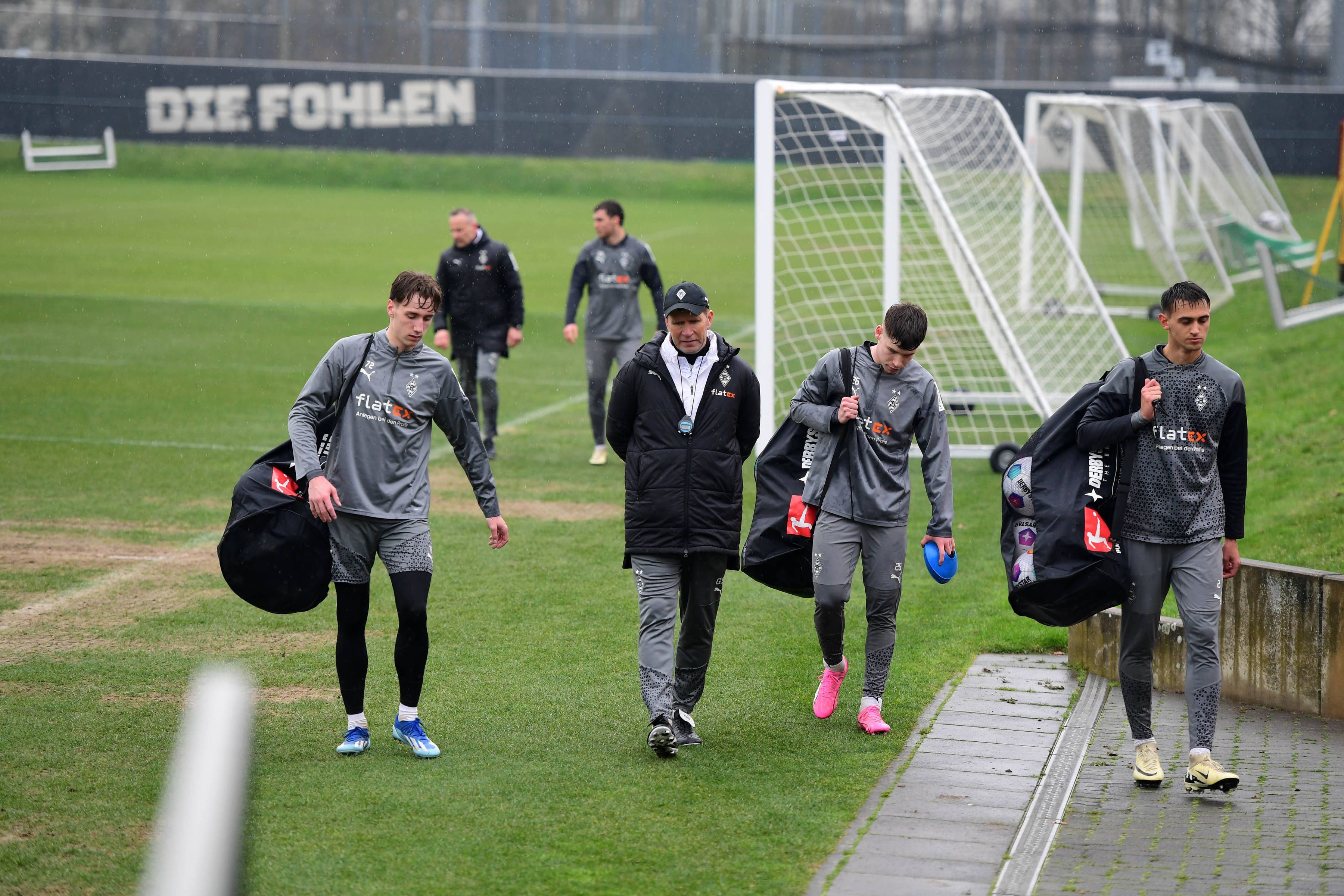 Junge Spieler von Borussia Mönchengladbach tragen die Bälle vom Trainingsplatz.