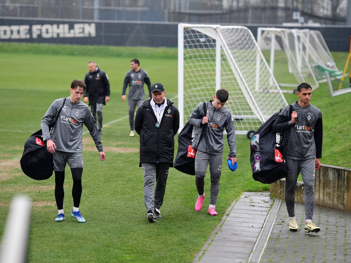 Junge Spieler von Borussia Mönchengladbach tragen die Bälle vom Trainingsplatz.