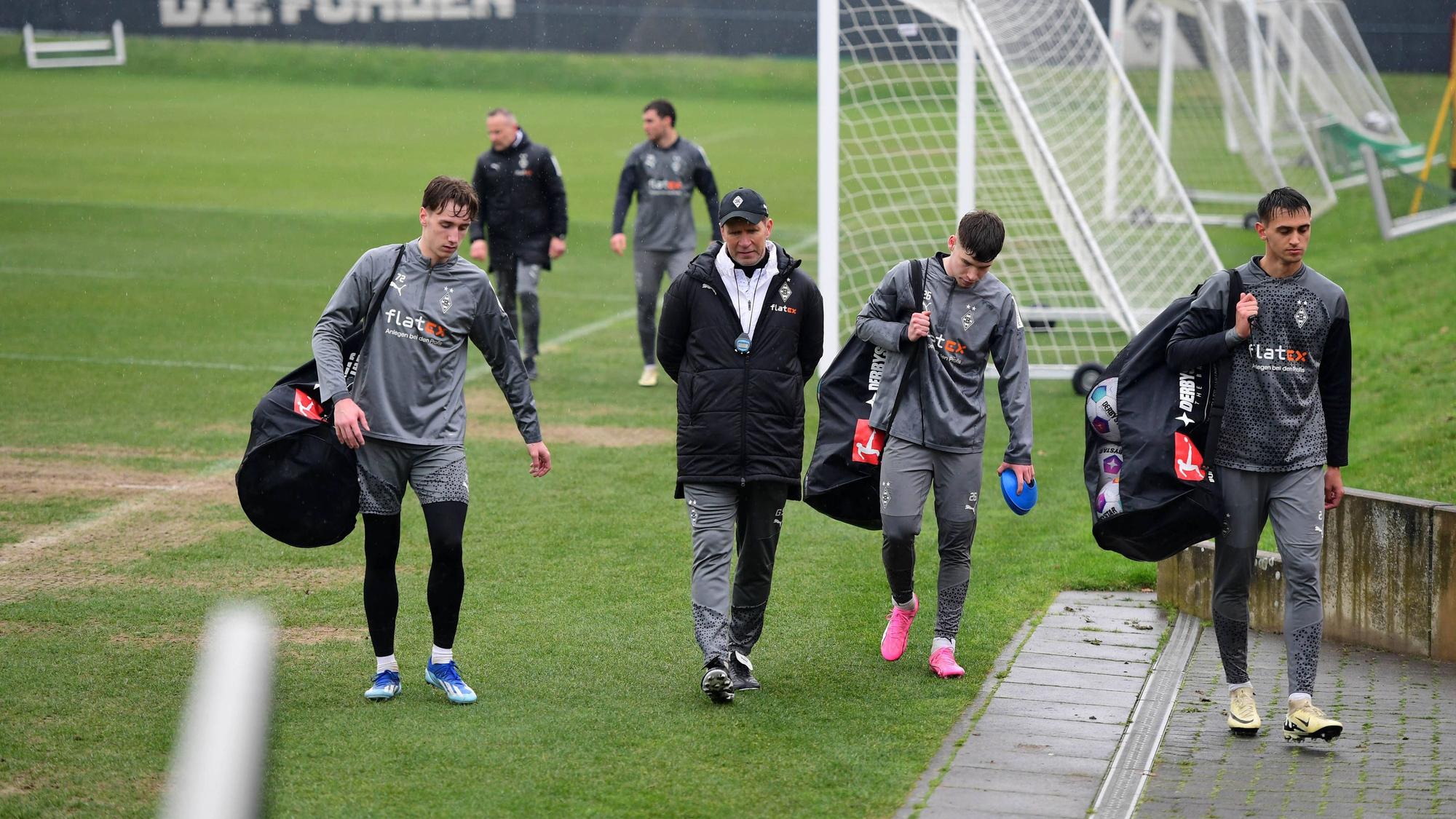 Junge Spieler von Borussia Mönchengladbach tragen die Bälle vom Trainingsplatz.
