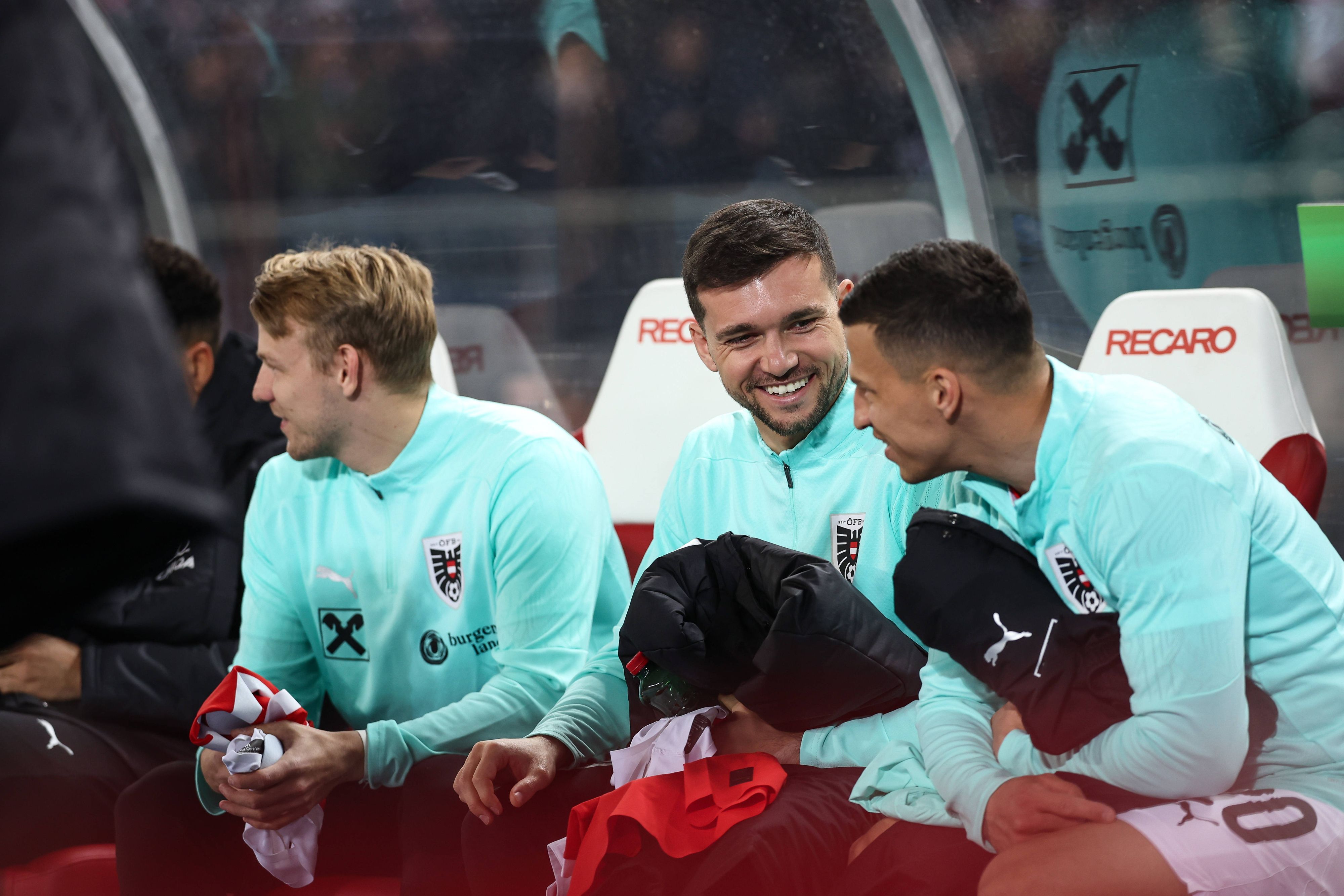 Stefan Lainer und Kevin Stöger sitzen auf der Bank und lachen miteinander.