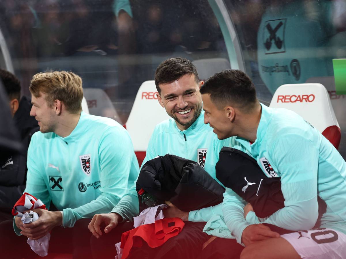 Stefan Lainer und Kevin Stöger sitzen auf der Bank und lachen miteinander.