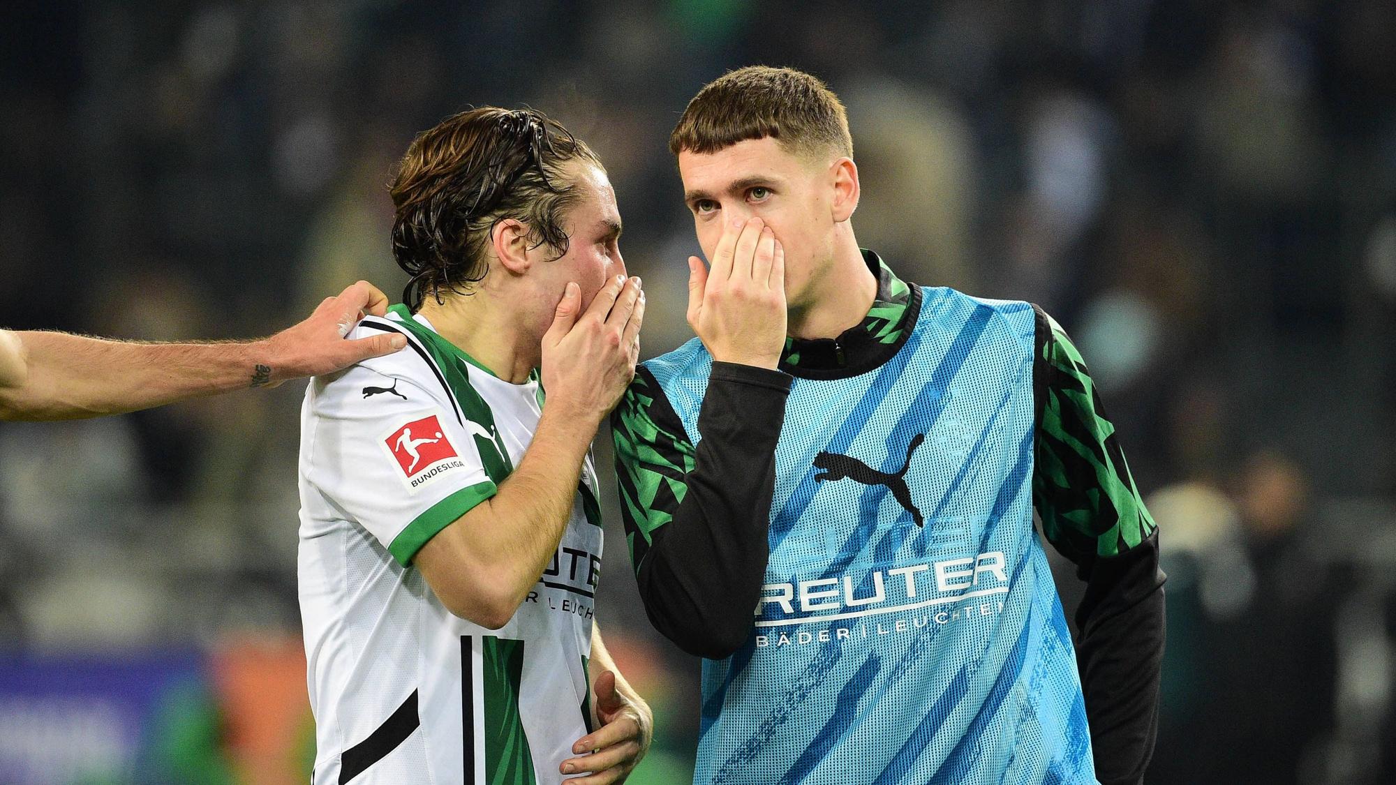 Die Gladbach-Profis Rocco Reitz und Philipp Sander unterhalten sich nach dem Bundesliga-Heimspiel gegen Werder Bremen mit vorgehaltener Hand vor dem Mund.
