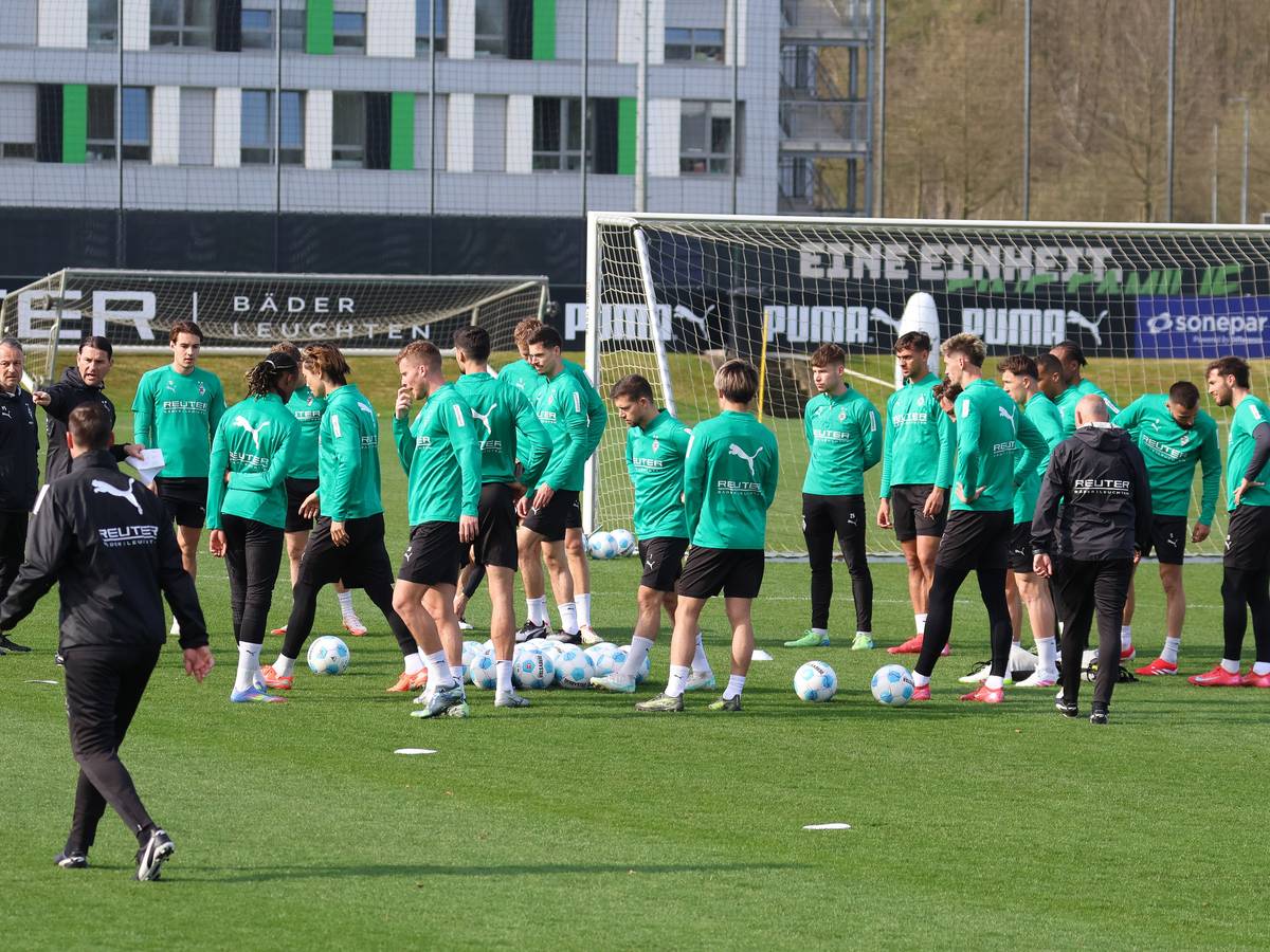 Die Gladbach-Profis und das Trainerteam auf dem Platz zum Training in der Sonne.