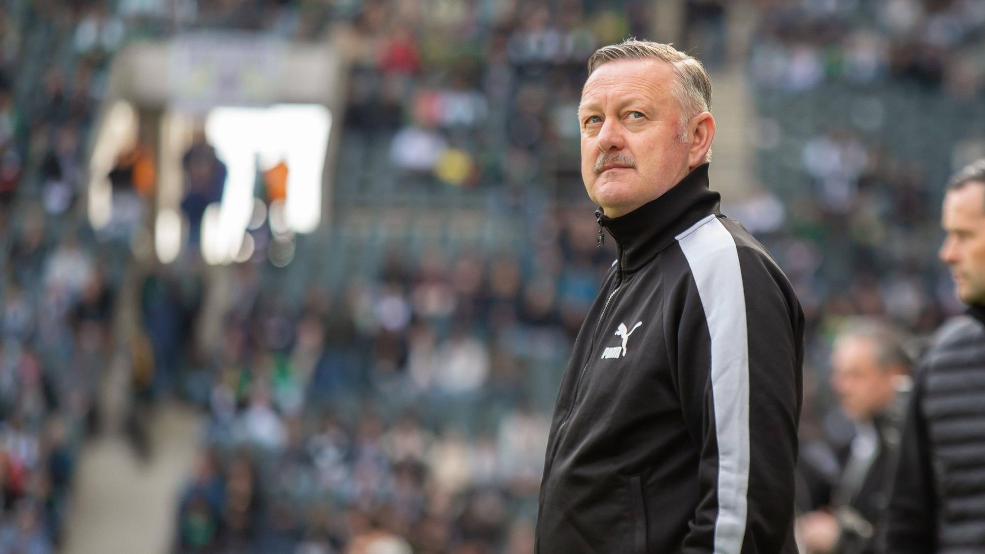 Roland Virkus schaut vor einem Bundesliga-Spiel konzentriert nach oben.