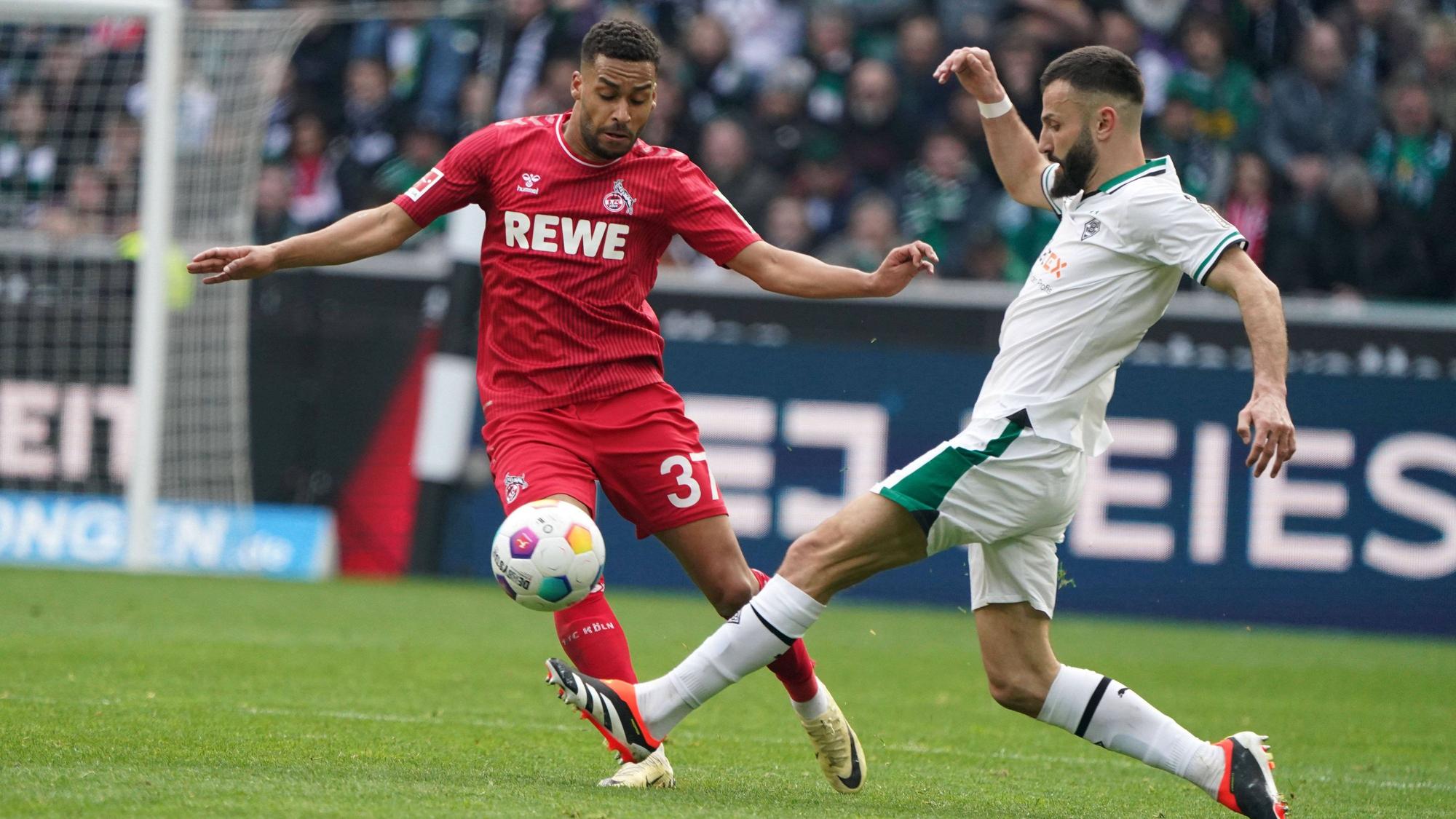 Linton Maina lupft den Ball über Franck Honorats Bein.
