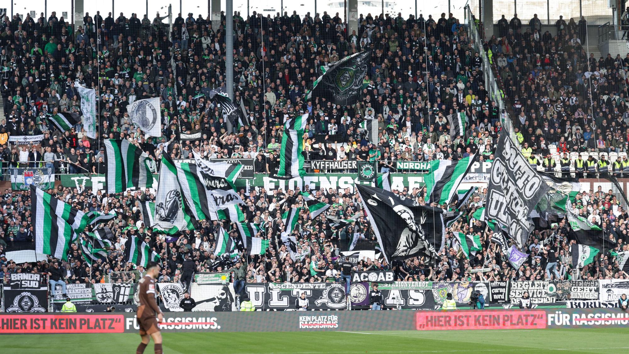 Gladbacher Auswärtsfans auf St. Pauli. Vorne steht auf einer Bande „Hier ist kein Platz für Rassismus.“