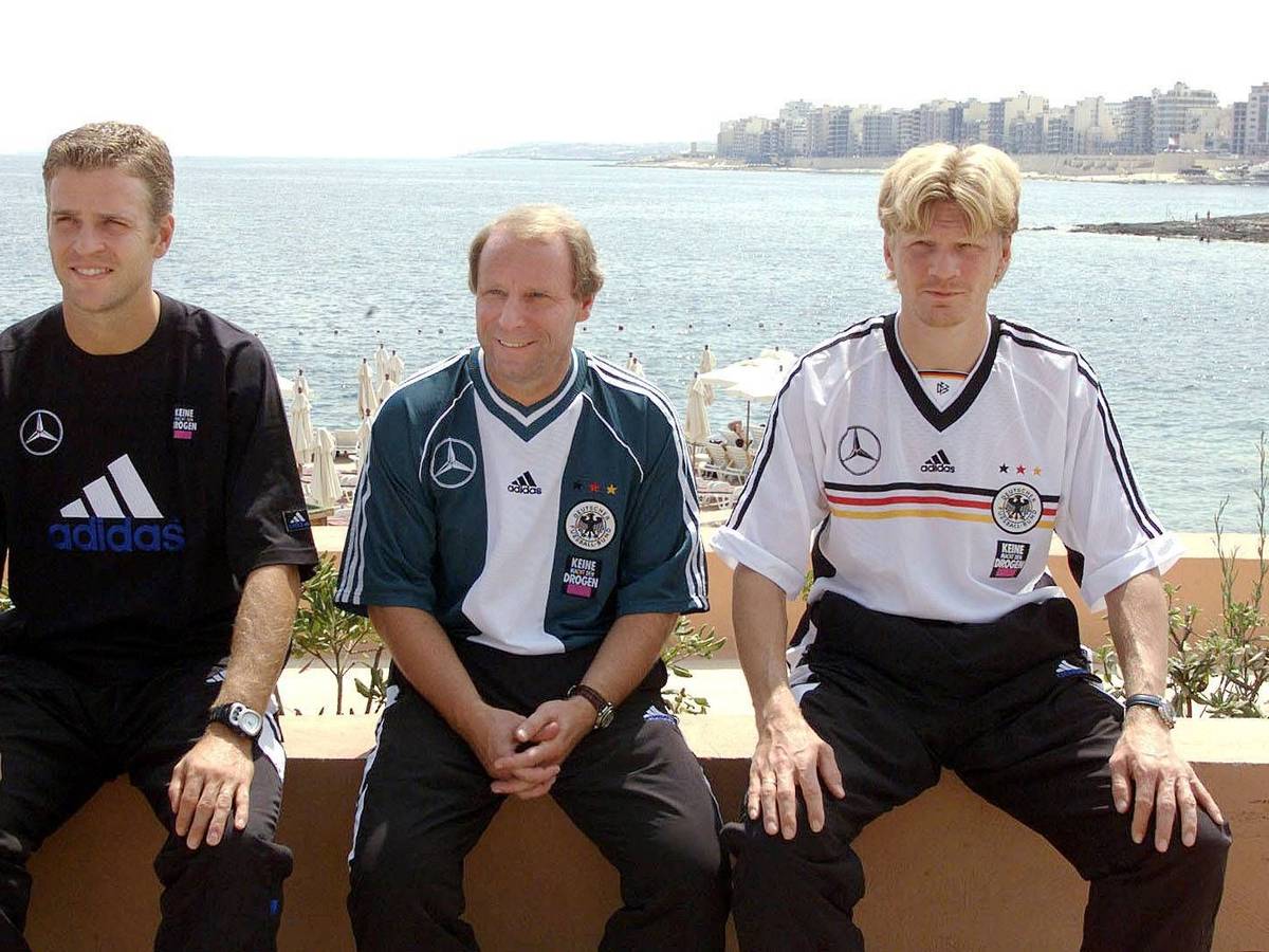 Oliver Bierhoff, Berti Vogts und Stefan Effenberg sitzen in DFB-Klamotten am Meer.