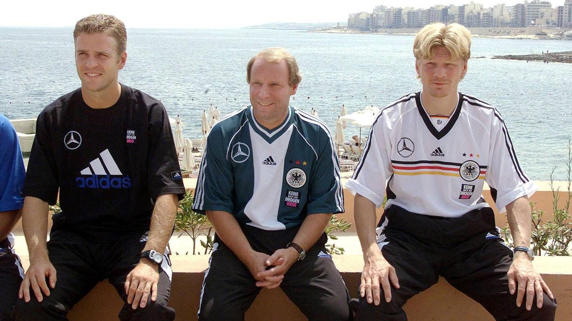Oliver Bierhoff, Berti Vogts und Stefan Effenberg sitzen in DFB-Klamotten am Meer.