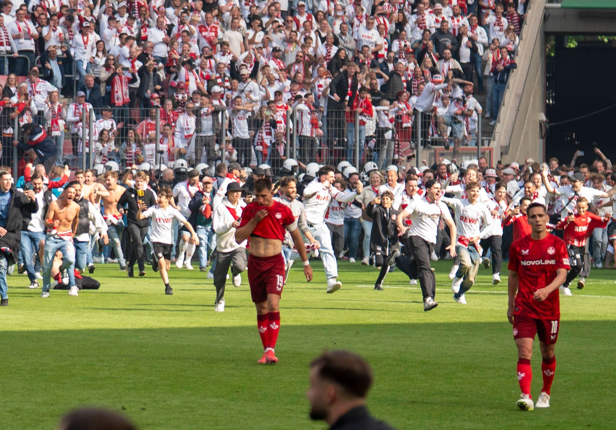 Der 1. FC Köln mit dem Platzsturm, während Kaiserslautern-Spieler den Platz enttäuscht verlassen.