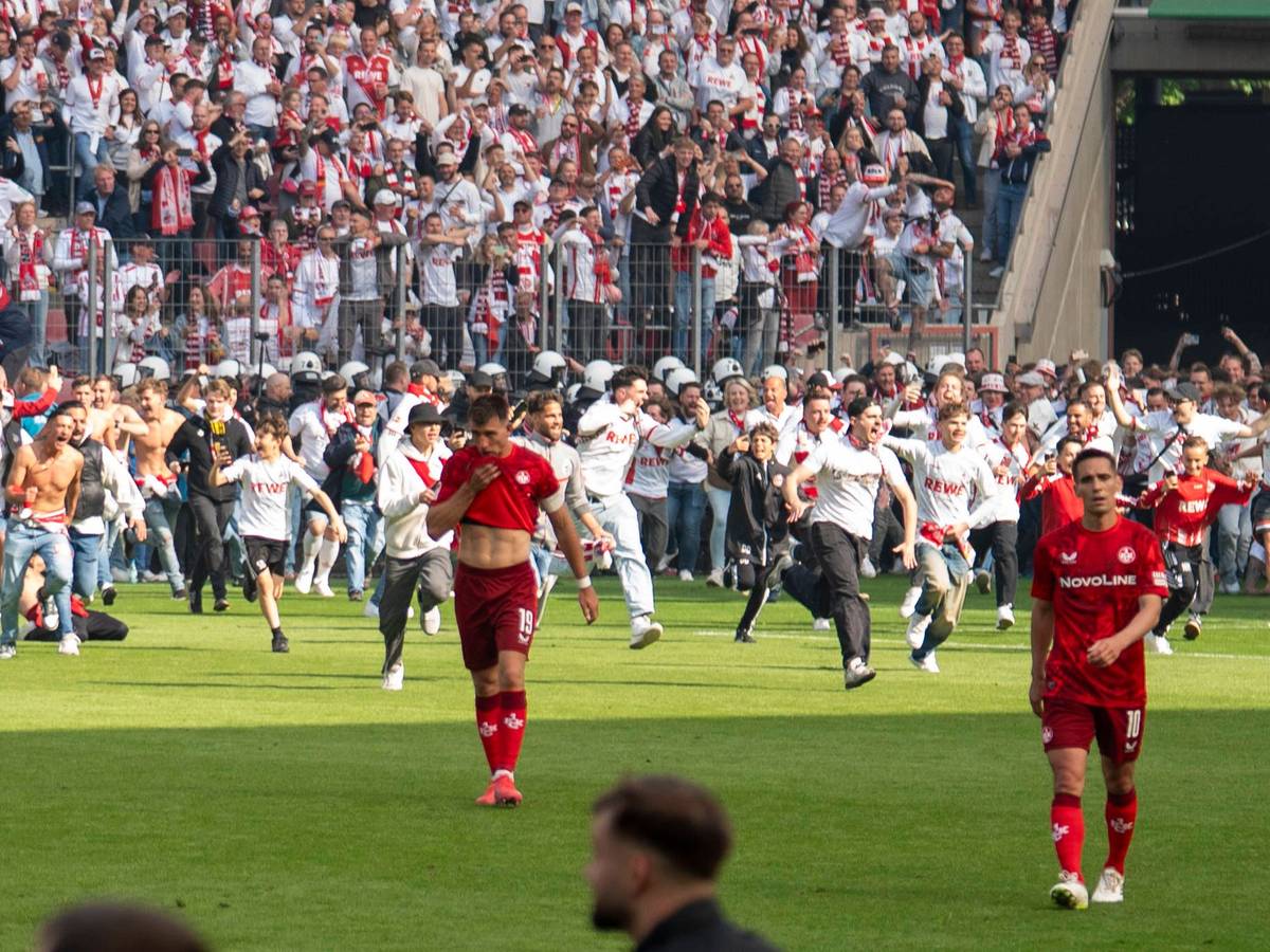Der 1. FC Köln mit dem Platzsturm, während Kaiserslautern-Spieler den Platz enttäuscht verlassen.