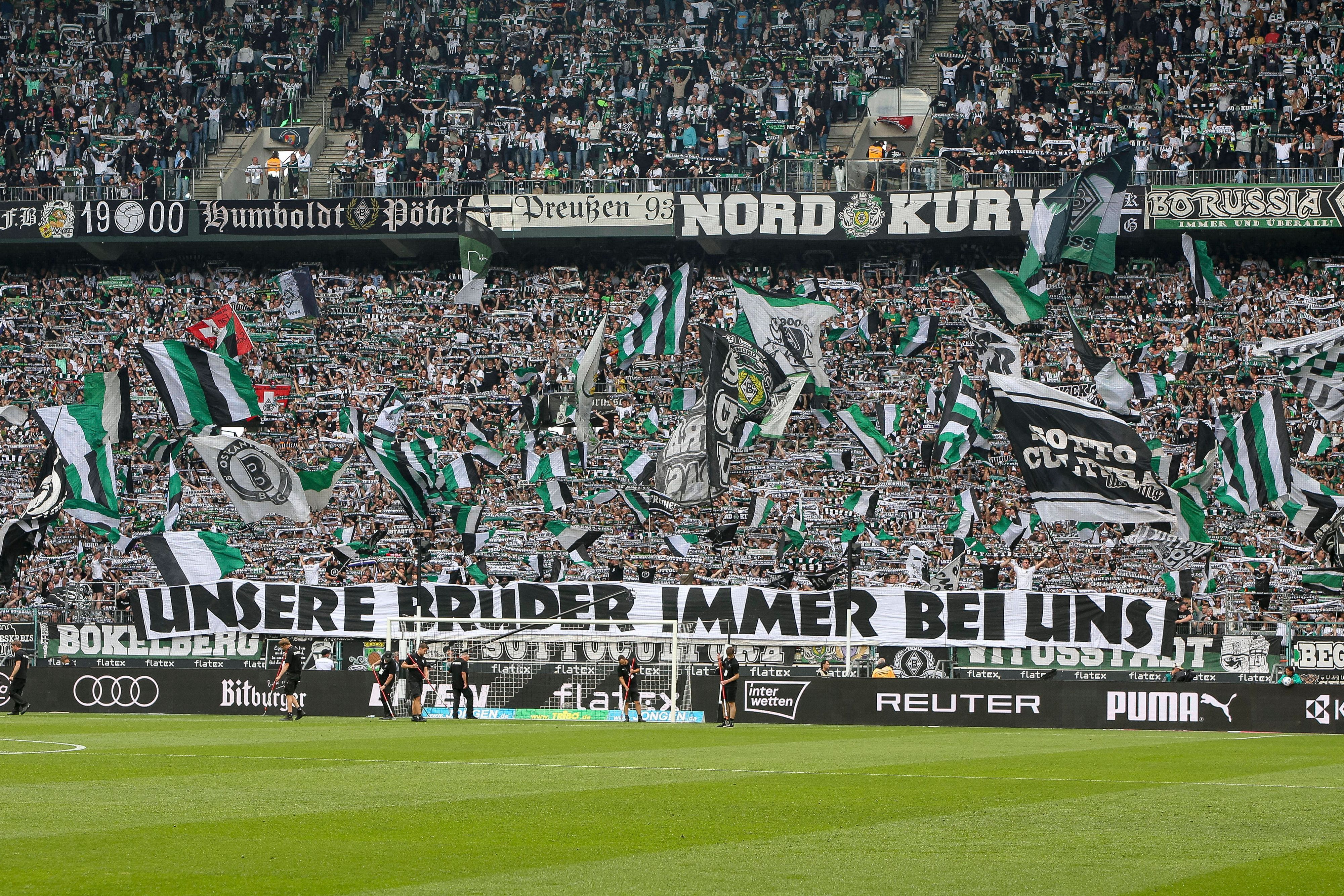 Fans von Borussia Mönchengladbach mit einem Banner und einem Meer aus Fahnen.