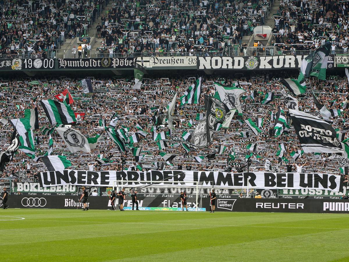 Fans von Borussia Mönchengladbach mit einem Banner und einem Meer aus Fahnen.