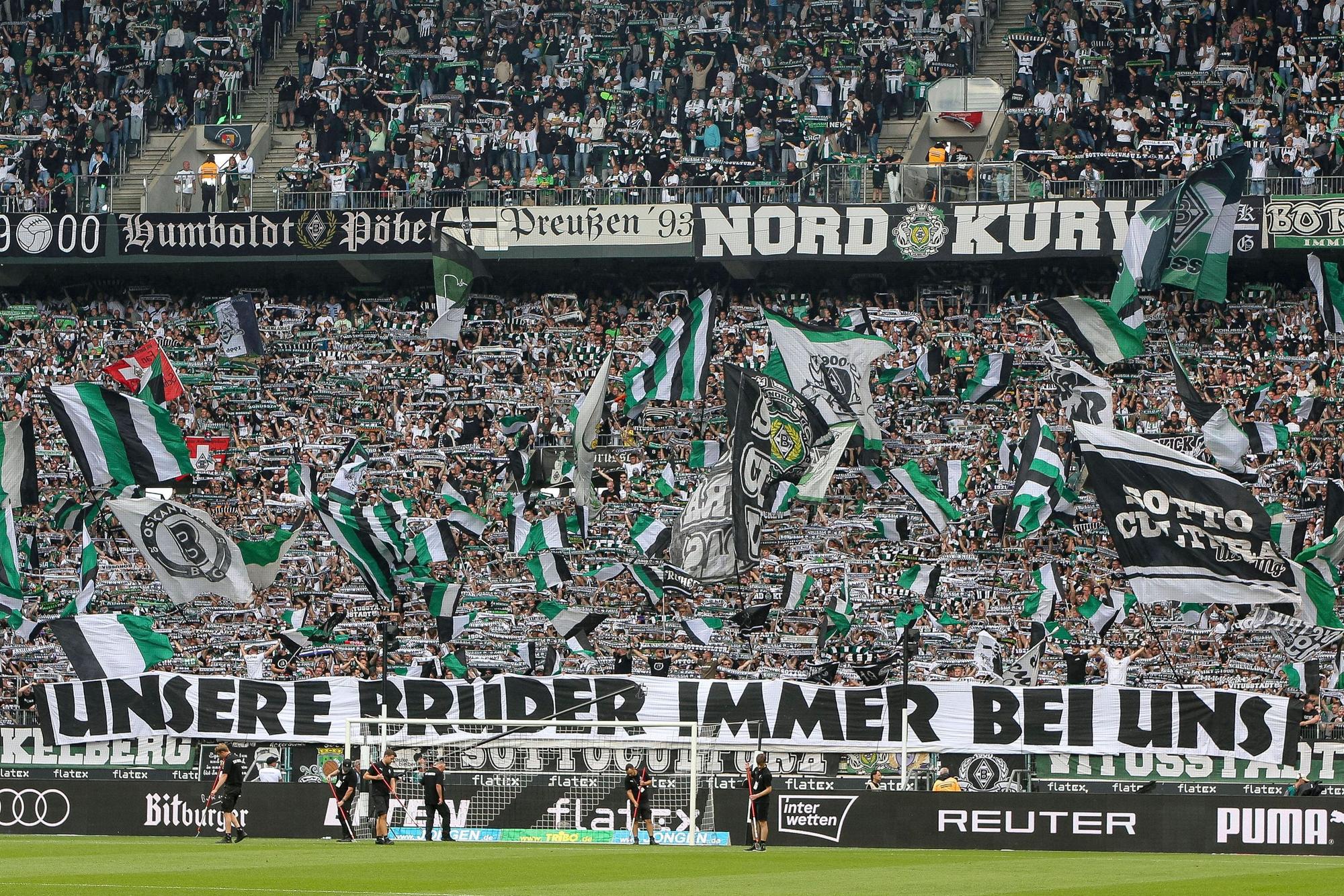 Fans von Borussia Mönchengladbach mit einem Banner und einem Meer aus Fahnen.