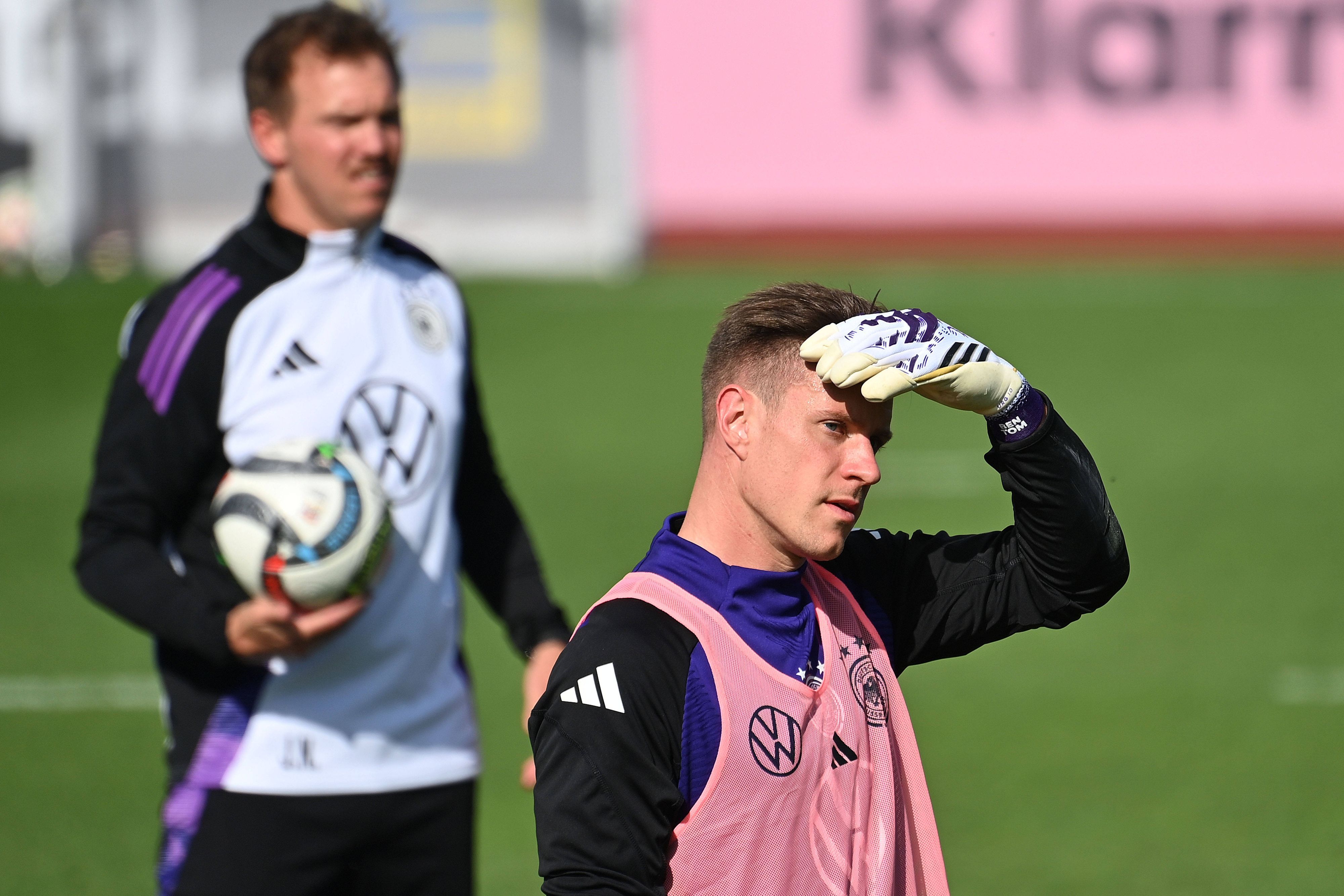 Marc-Andre ter Stegen schützt beim Training seine Augen mit der Hand vor der Sonne, im Hintergrund steht Julian Nagelsmann.
